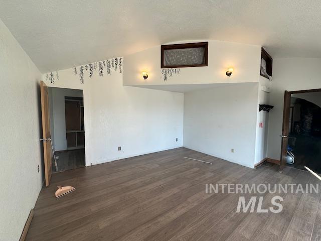 Unfurnished living room featuring wood finished floors and vaulted ceiling