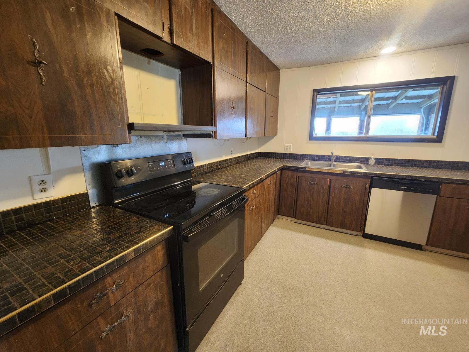 Kitchen with black electric range oven, dishwasher, dark brown cabinets, a textured ceiling, and light floors