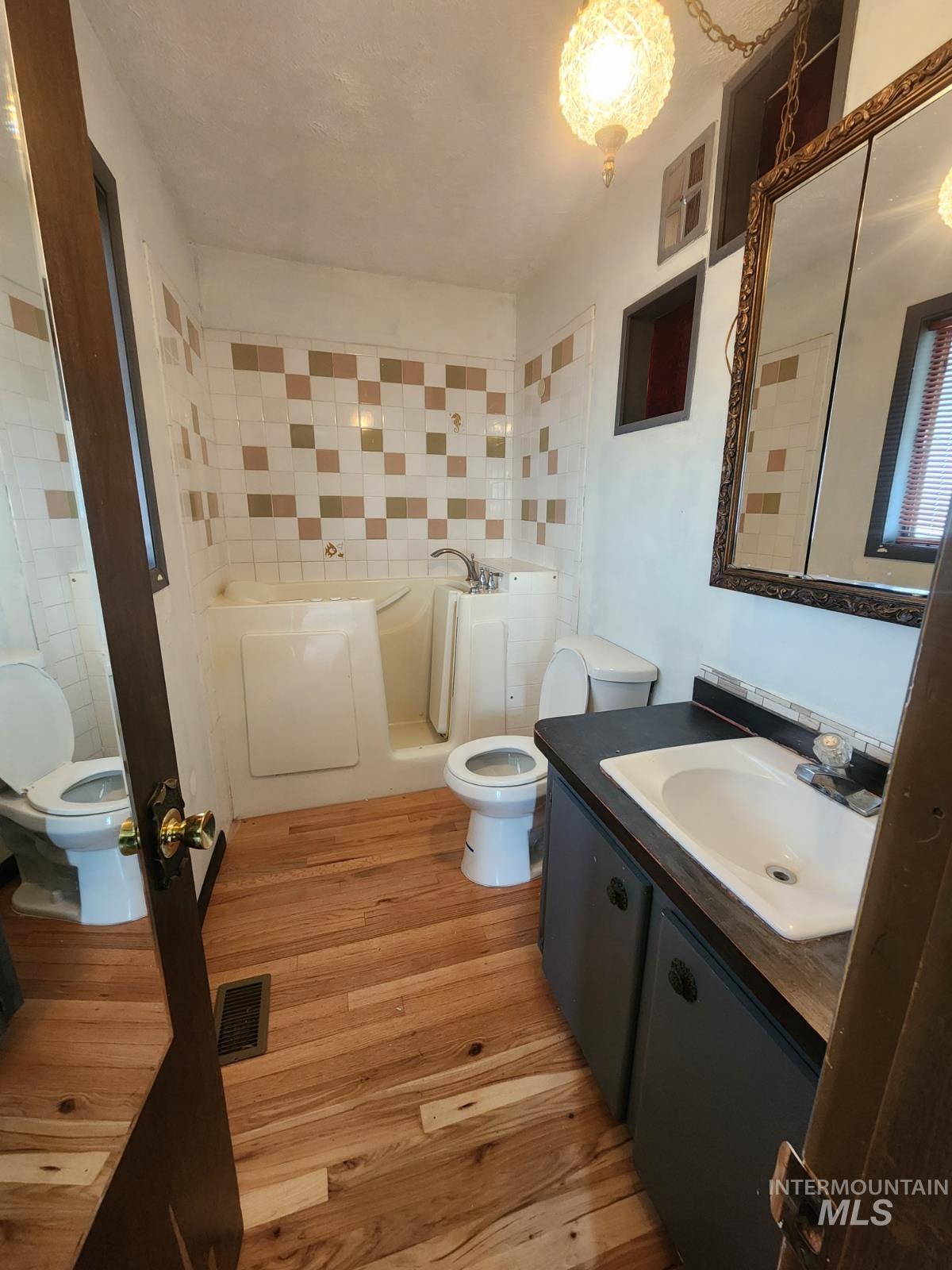 Full bath featuring vanity, a garden tub, and light wood-style flooring