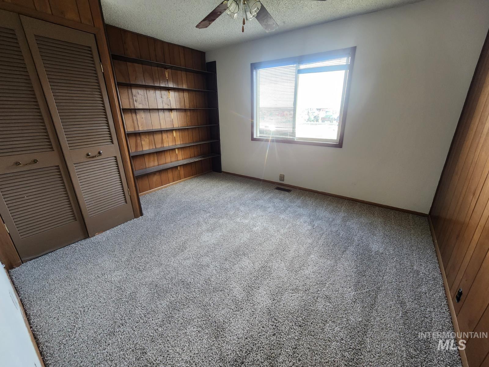 Unfurnished bedroom featuring a textured ceiling, carpet floors, a closet, and ceiling fan