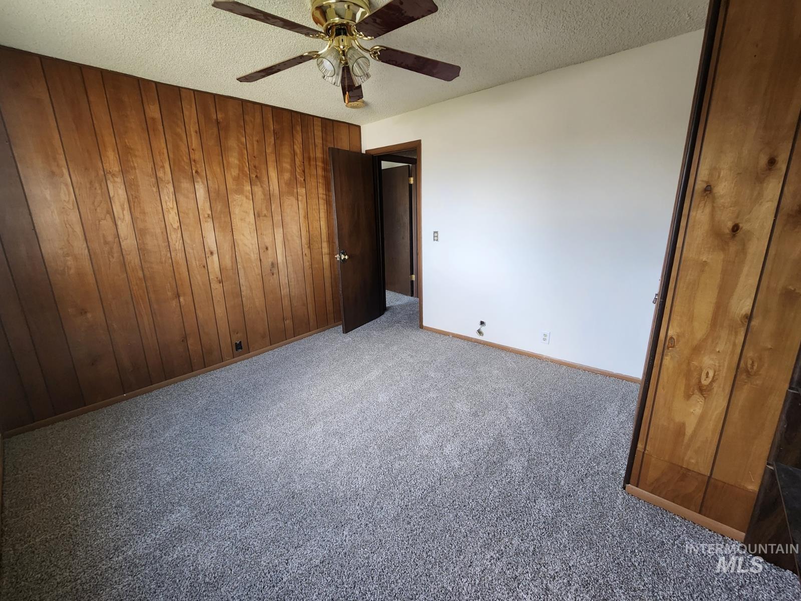 Spare room with wooden walls, carpet, and a textured ceiling