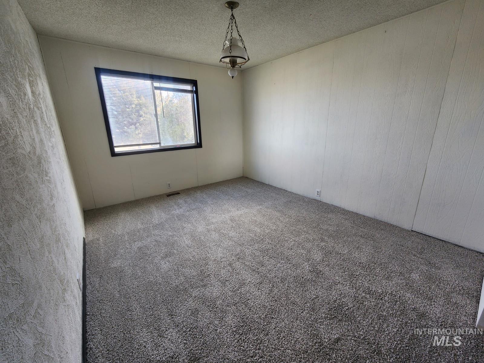 Carpeted spare room featuring a textured ceiling