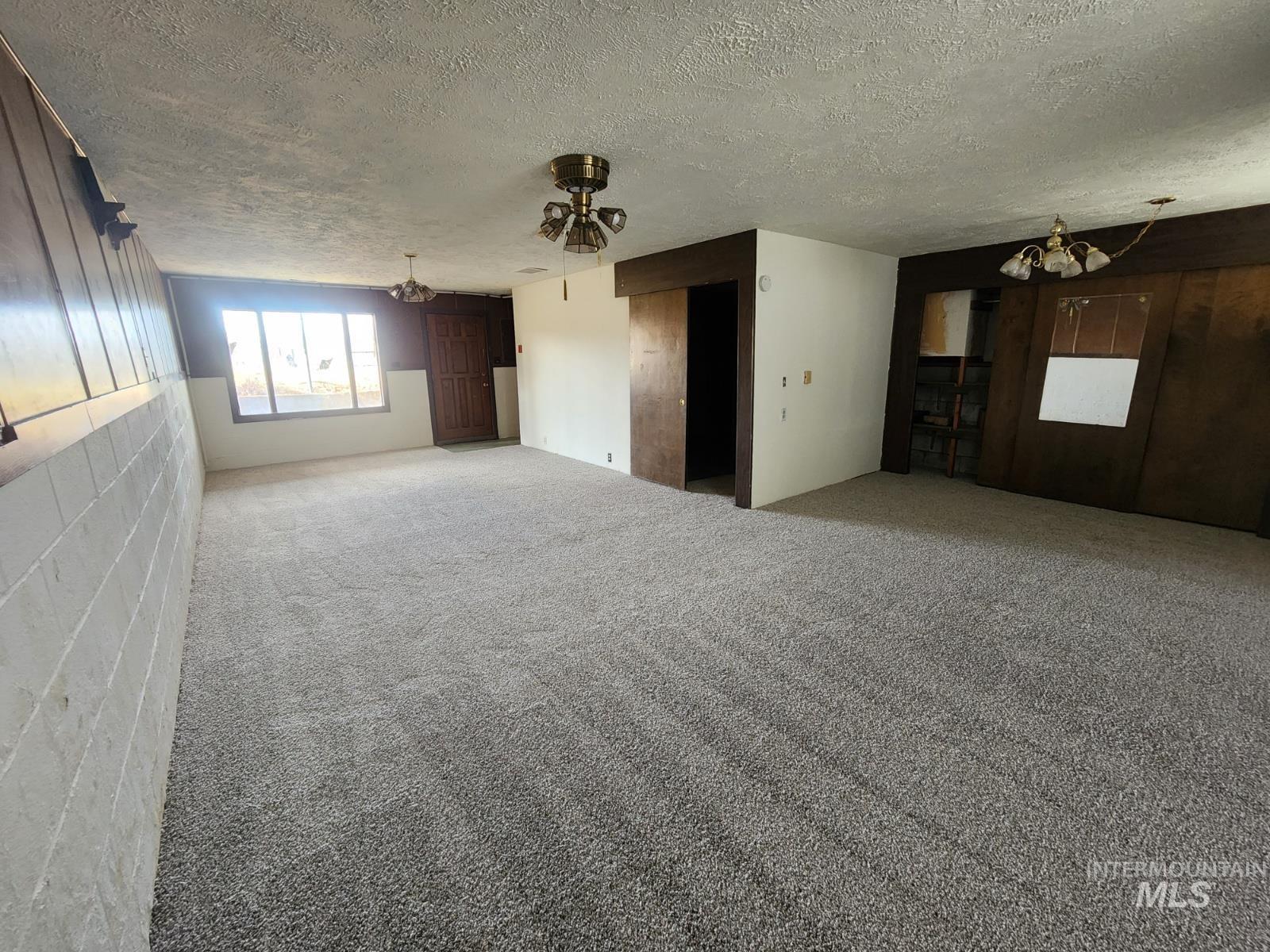 Carpeted spare room featuring a chandelier and a textured ceiling