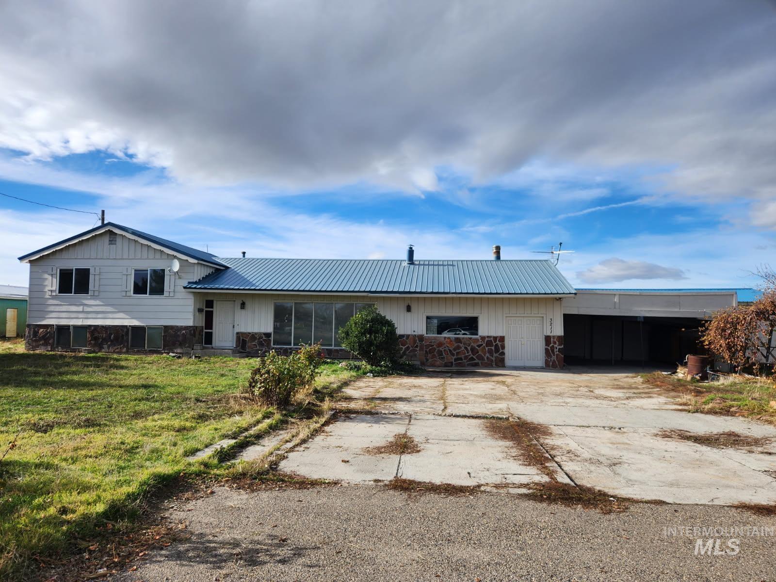View of front of home with stone siding, board and batten siding, a metal roof, and driveway