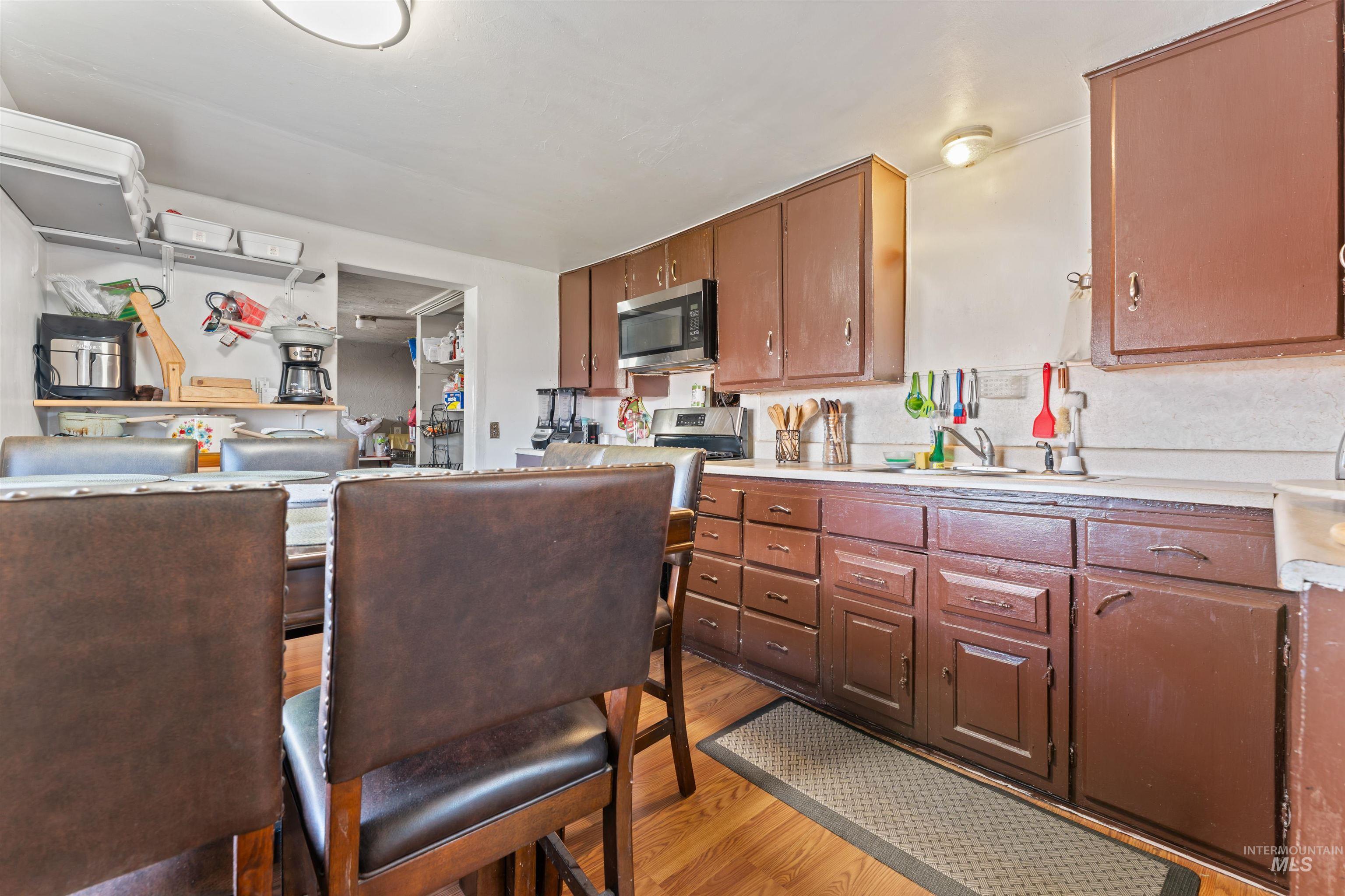 Kitchen featuring light countertops, light wood-style floors, stainless steel microwave, and brown cabinets