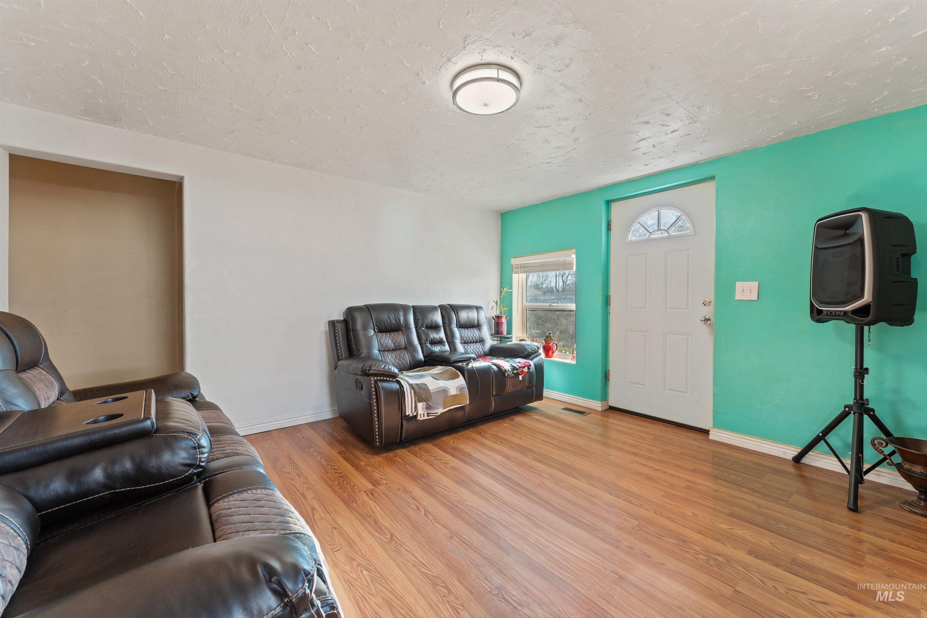 Living area with a textured ceiling and light wood-style flooring