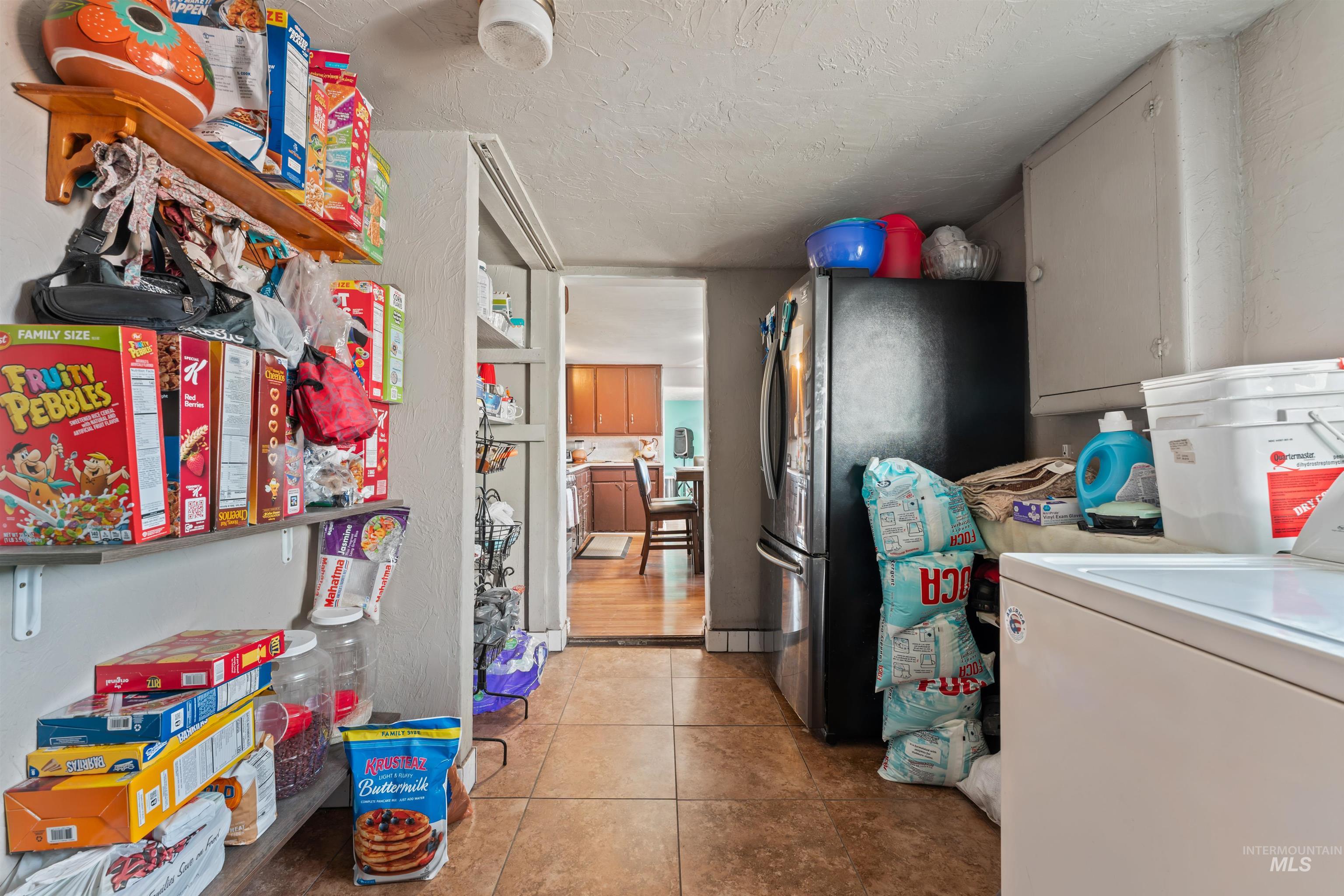 Laundry area featuring a textured ceiling and light tile patterned floors