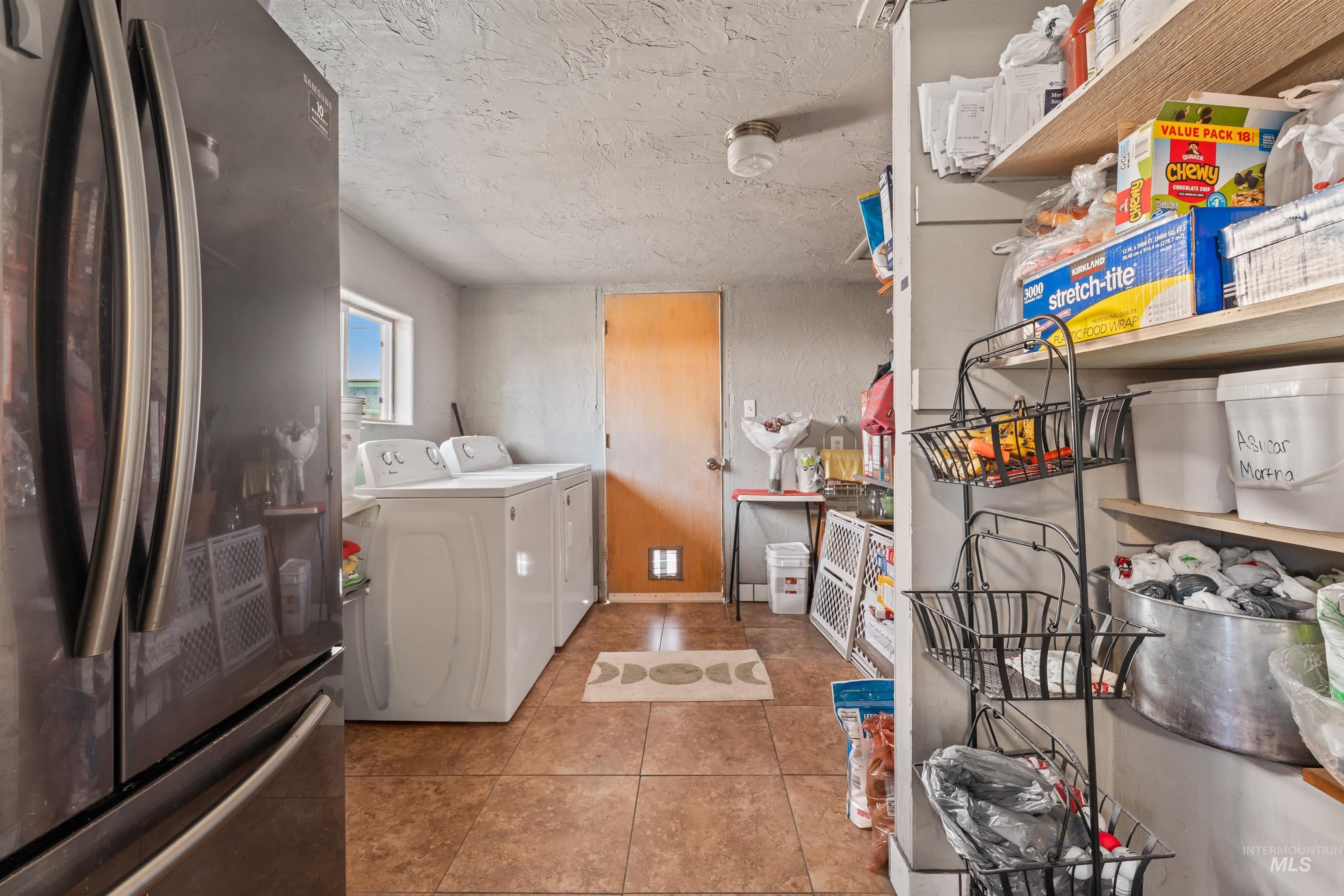 Laundry area with a textured ceiling, light tile patterned flooring, and washer and dryer
