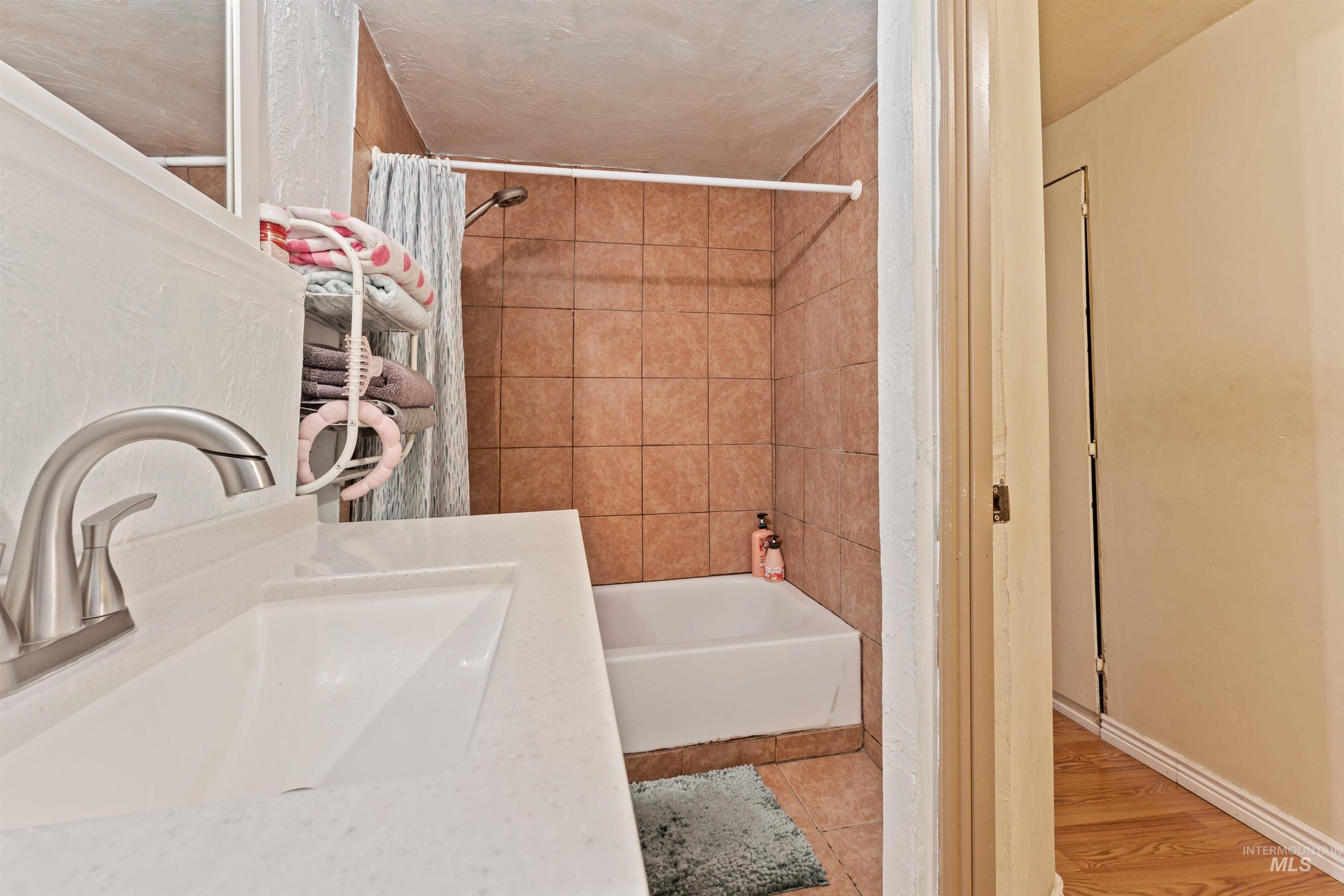 Full bath with shower / tub combo, vanity, and light tile patterned floors