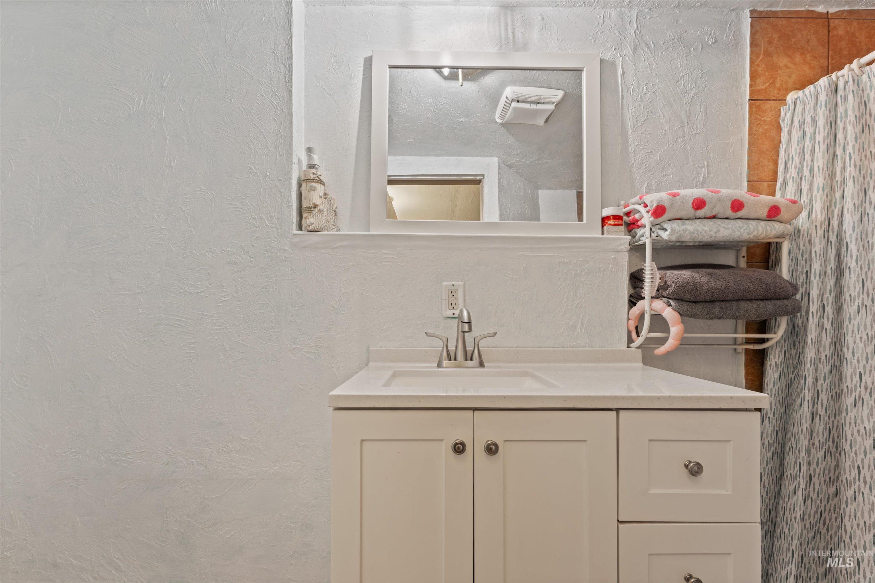 Bathroom featuring a textured wall, vanity, and a shower with shower curtain