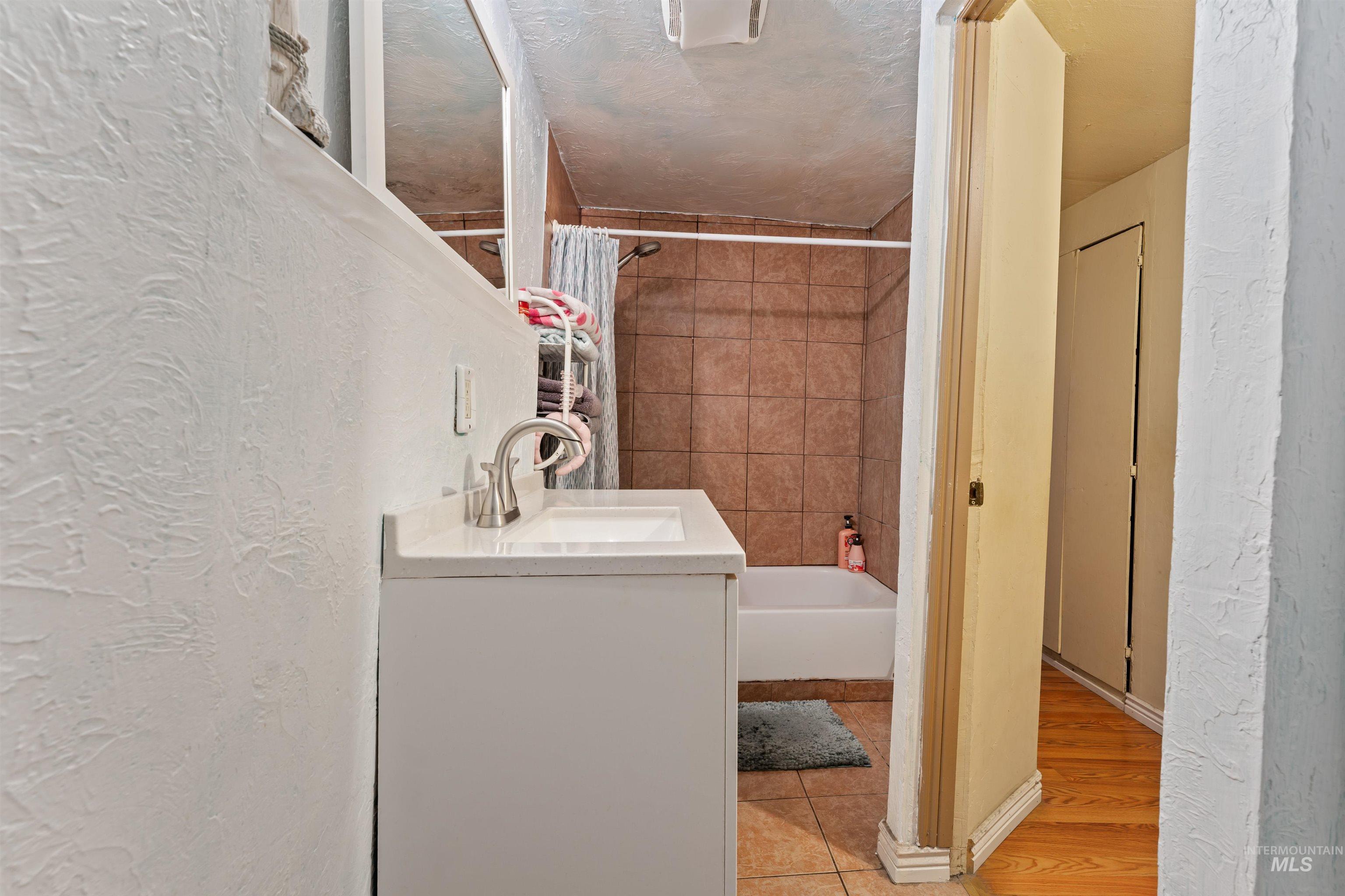 Washroom with a textured wall and light tile patterned flooring