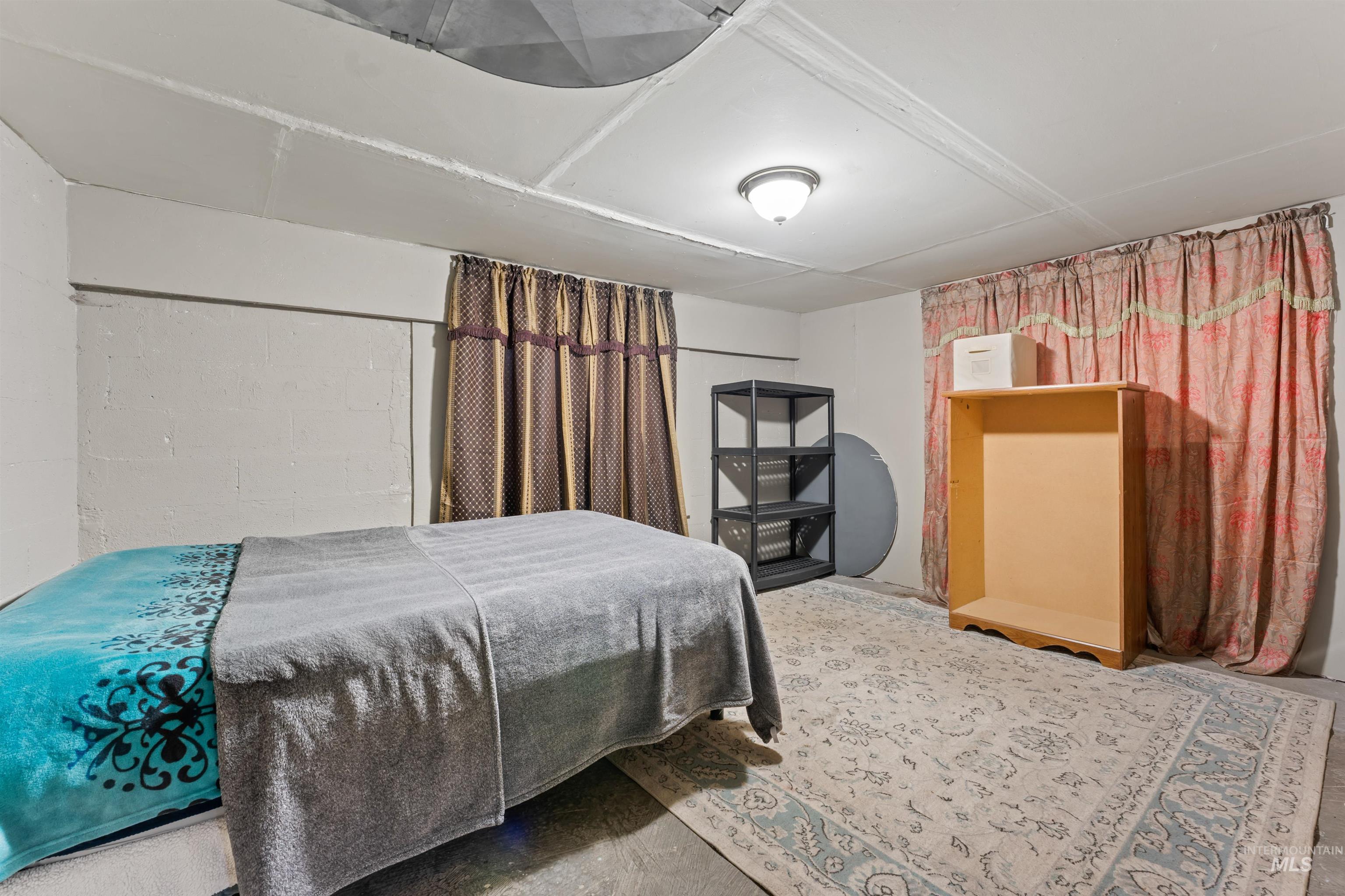 Bedroom featuring concrete flooring and concrete block wall