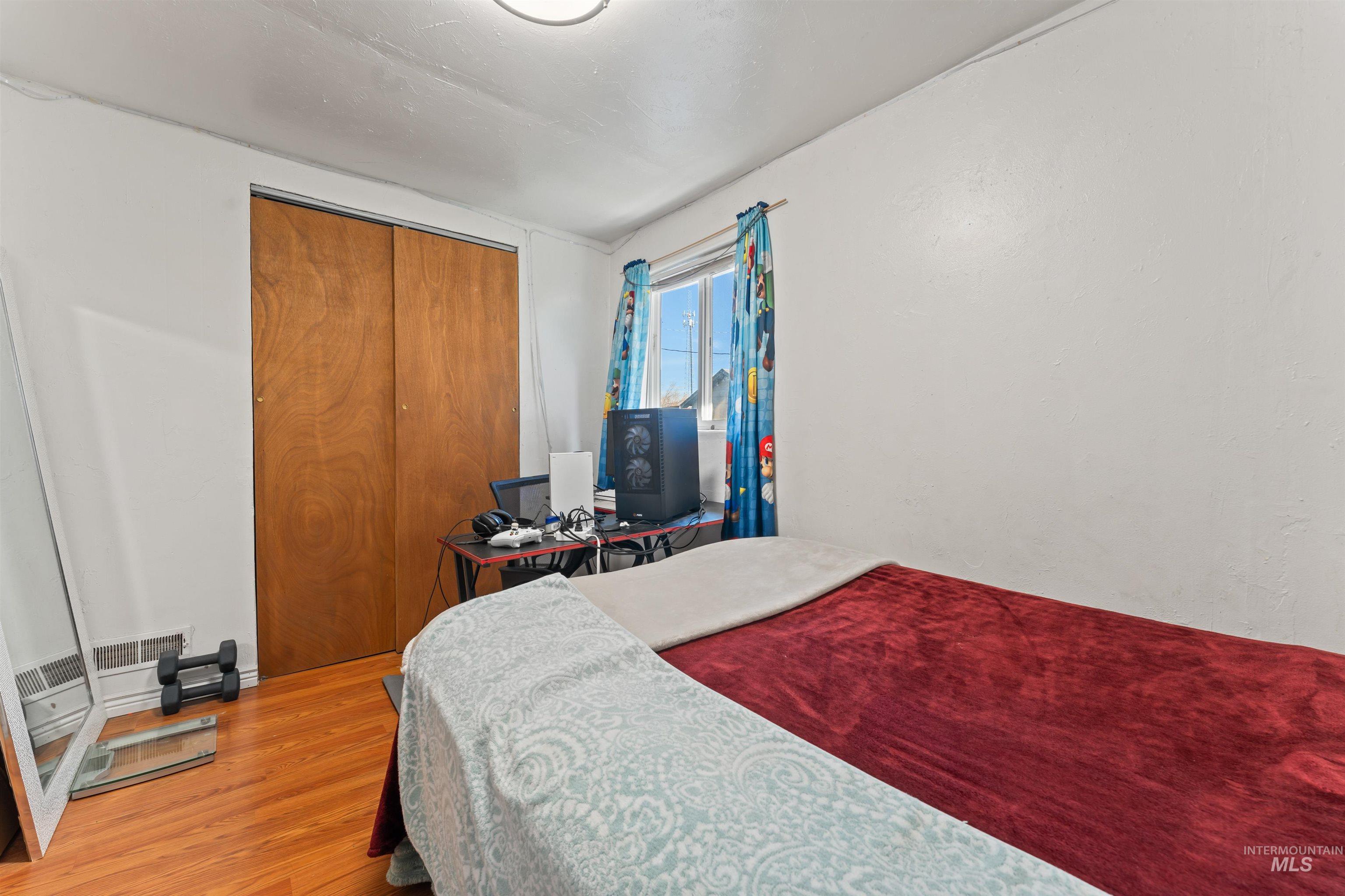 Bedroom featuring a closet, wood finished floors, and a desk