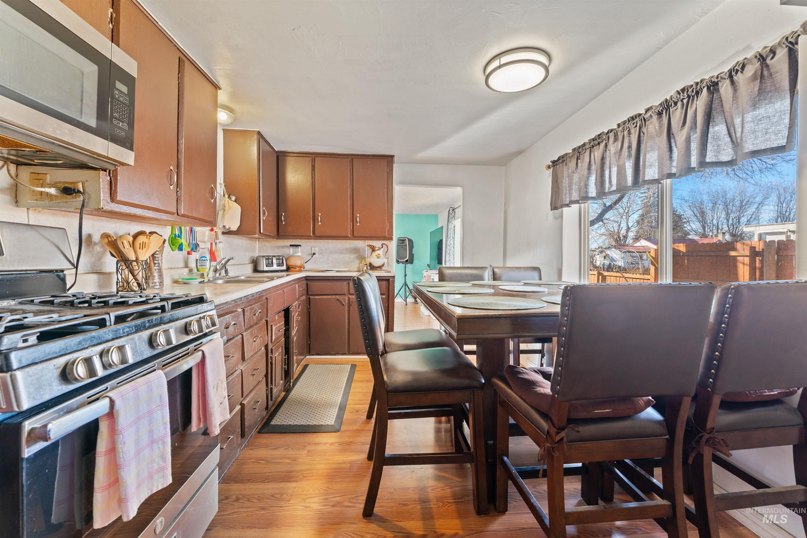 Kitchen featuring stainless steel appliances, light countertops, brown cabinets, tasteful backsplash, and light wood-type flooring