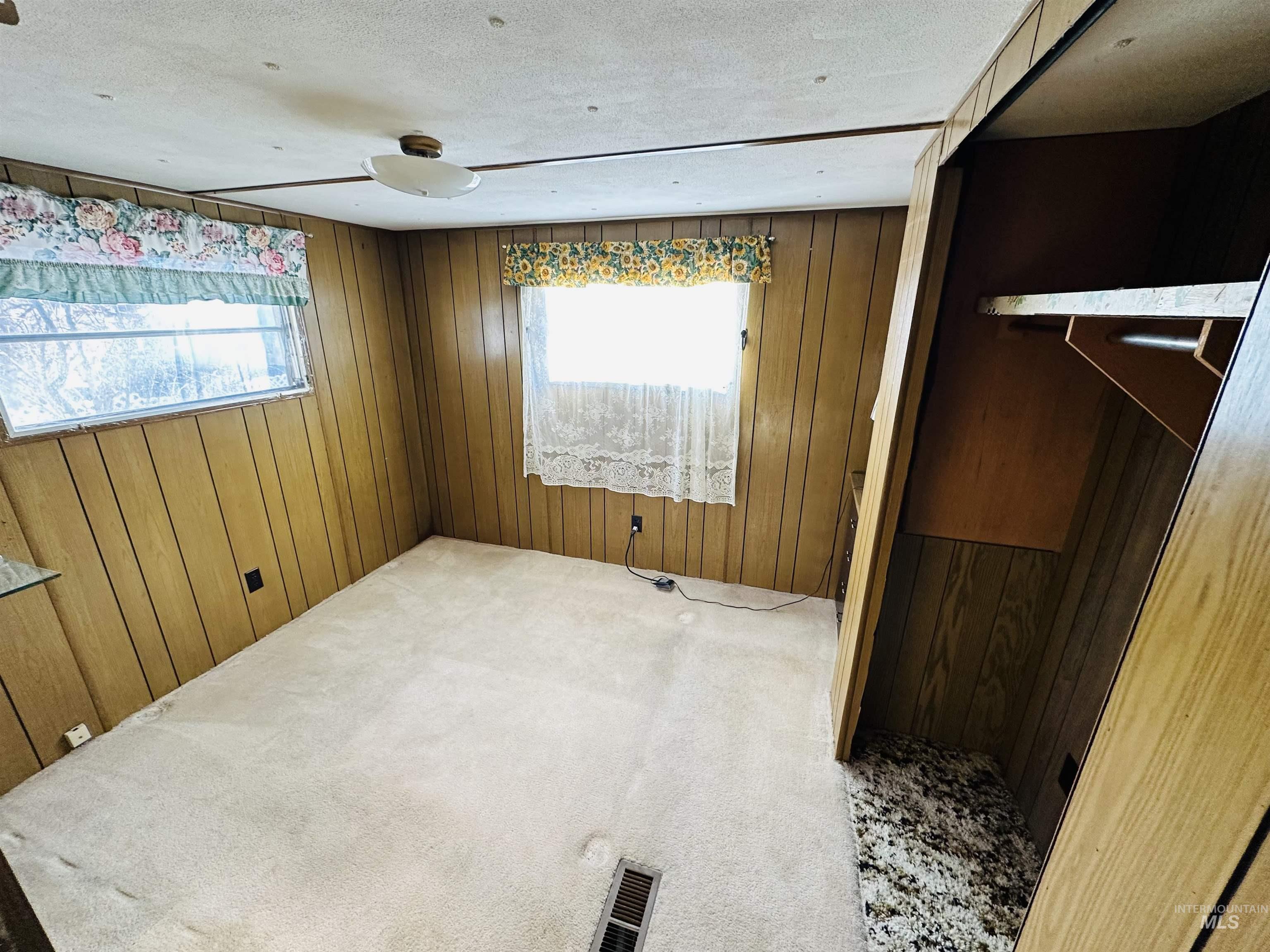 Unfurnished bedroom with wood walls, carpet floors, and a textured ceiling