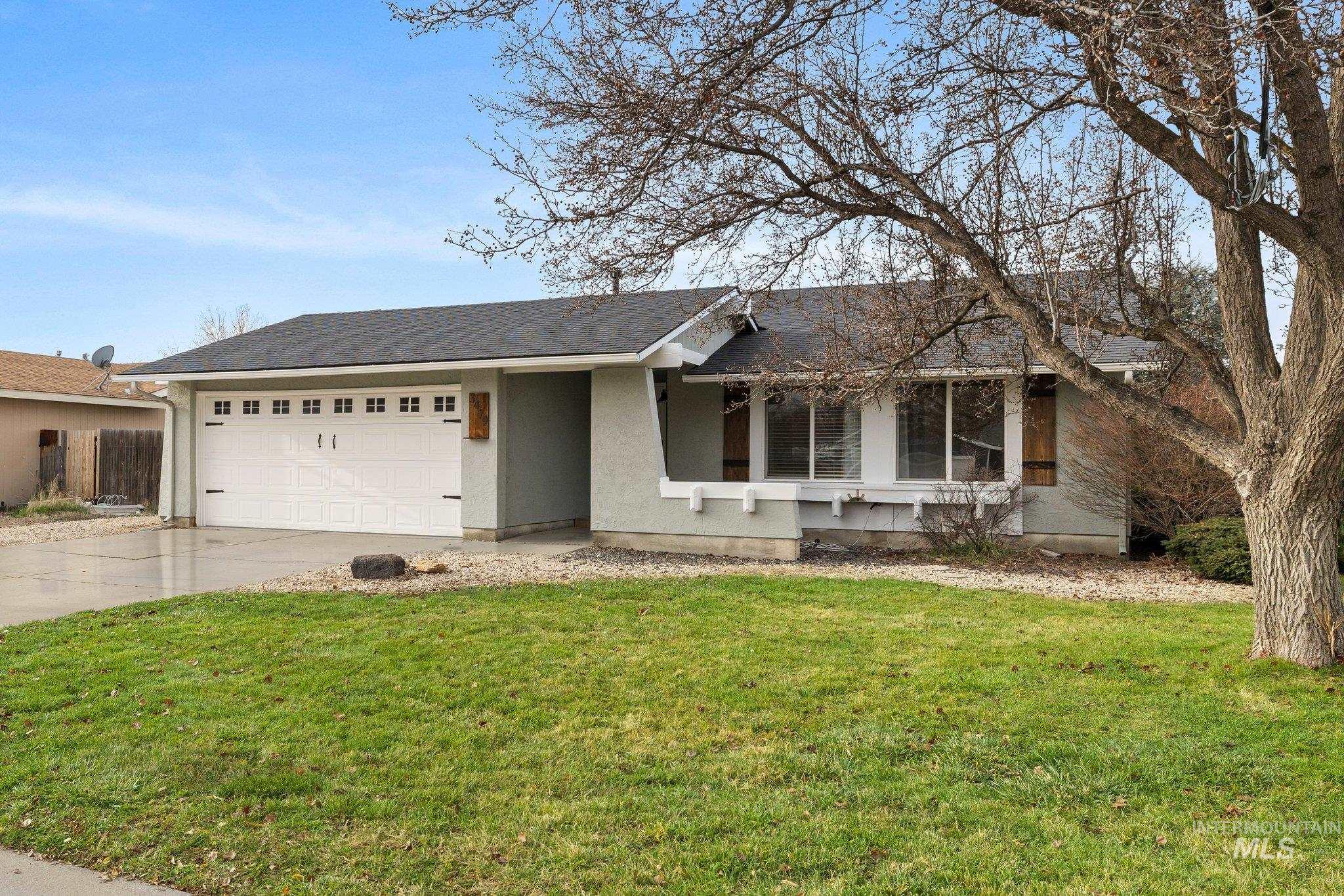 Ranch-style home with concrete driveway, a front lawn, roof with shingles, stucco siding, and an attached garage