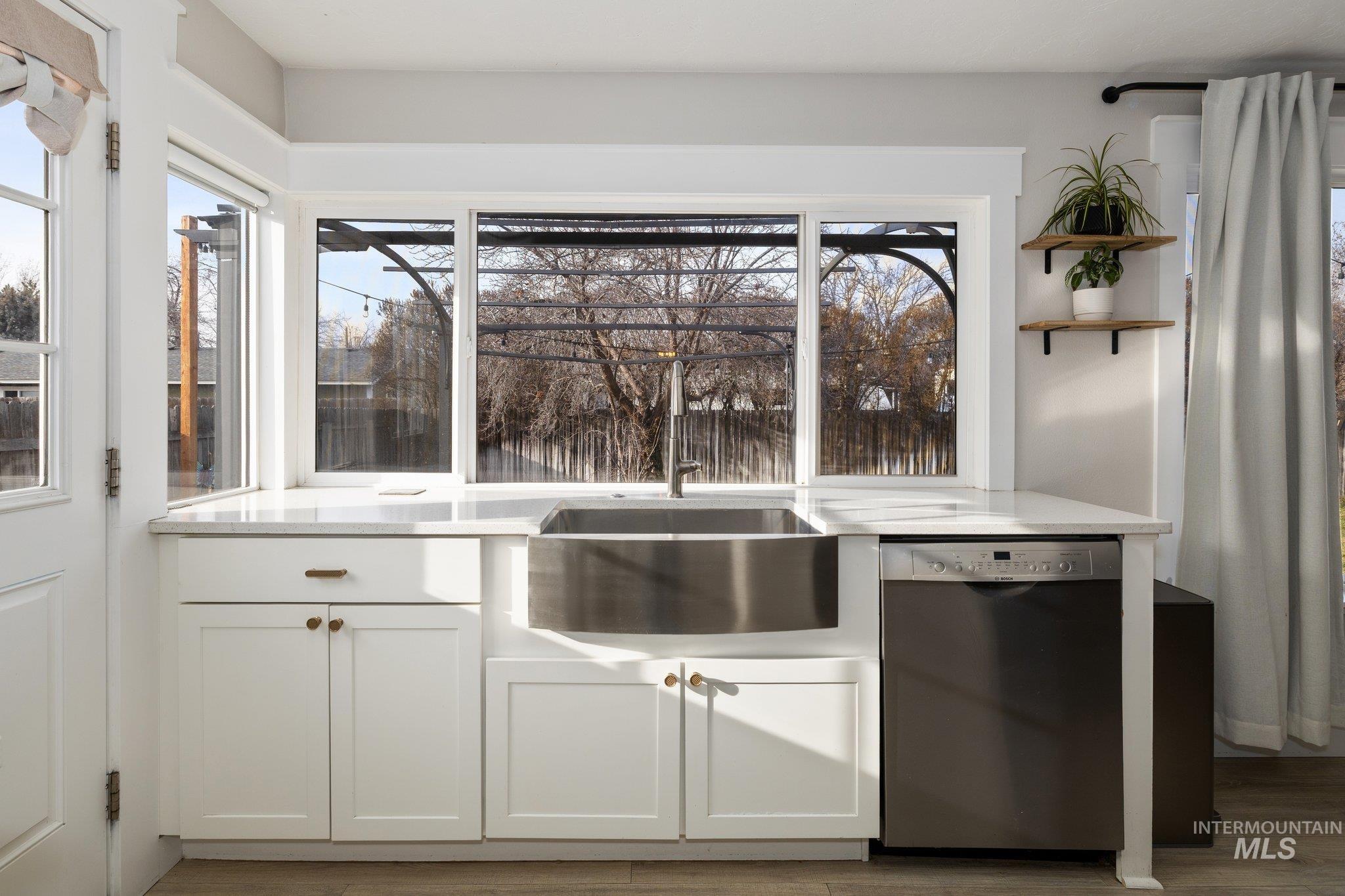 Kitchen featuring white cabinets, dishwasher, open shelves, light stone counters, and dark wood-style flooring