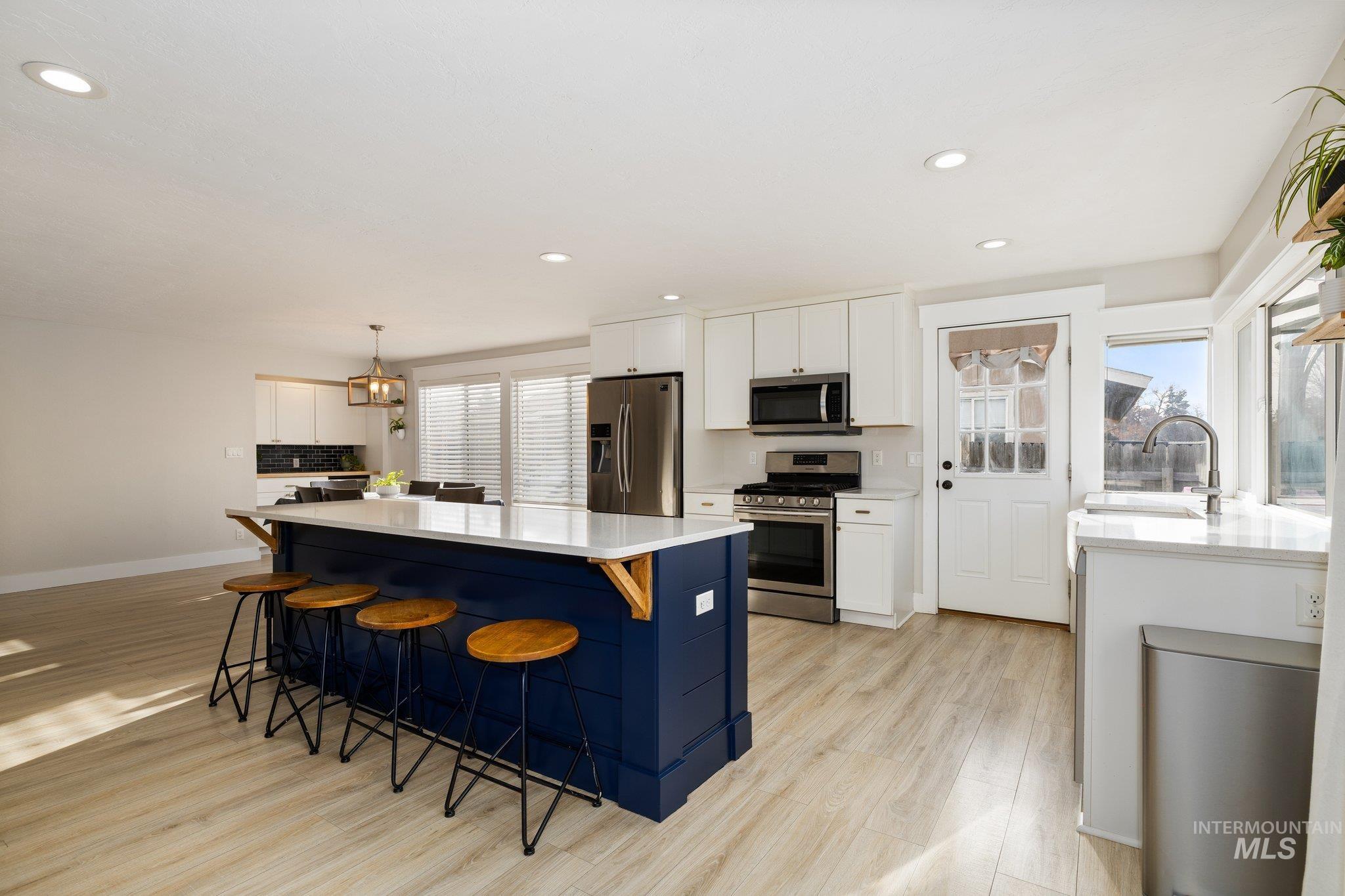 Kitchen featuring white cabinets, a kitchen breakfast bar, appliances with stainless steel finishes, a kitchen island, and recessed lighting