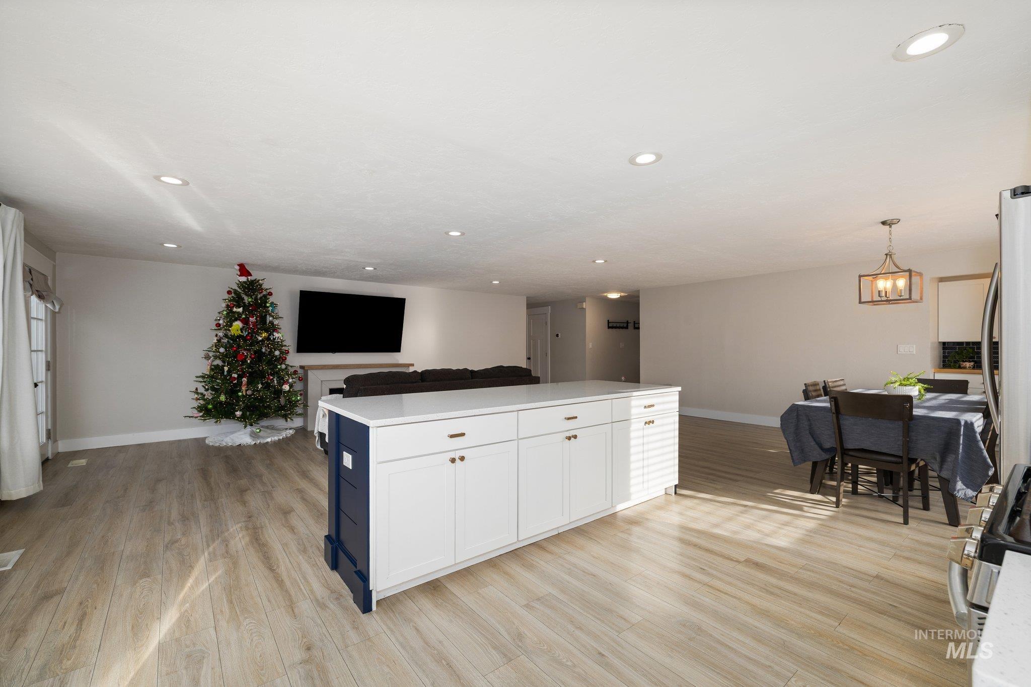 Kitchen featuring open floor plan, decorative light fixtures, light wood-type flooring, white cabinetry, and recessed lighting