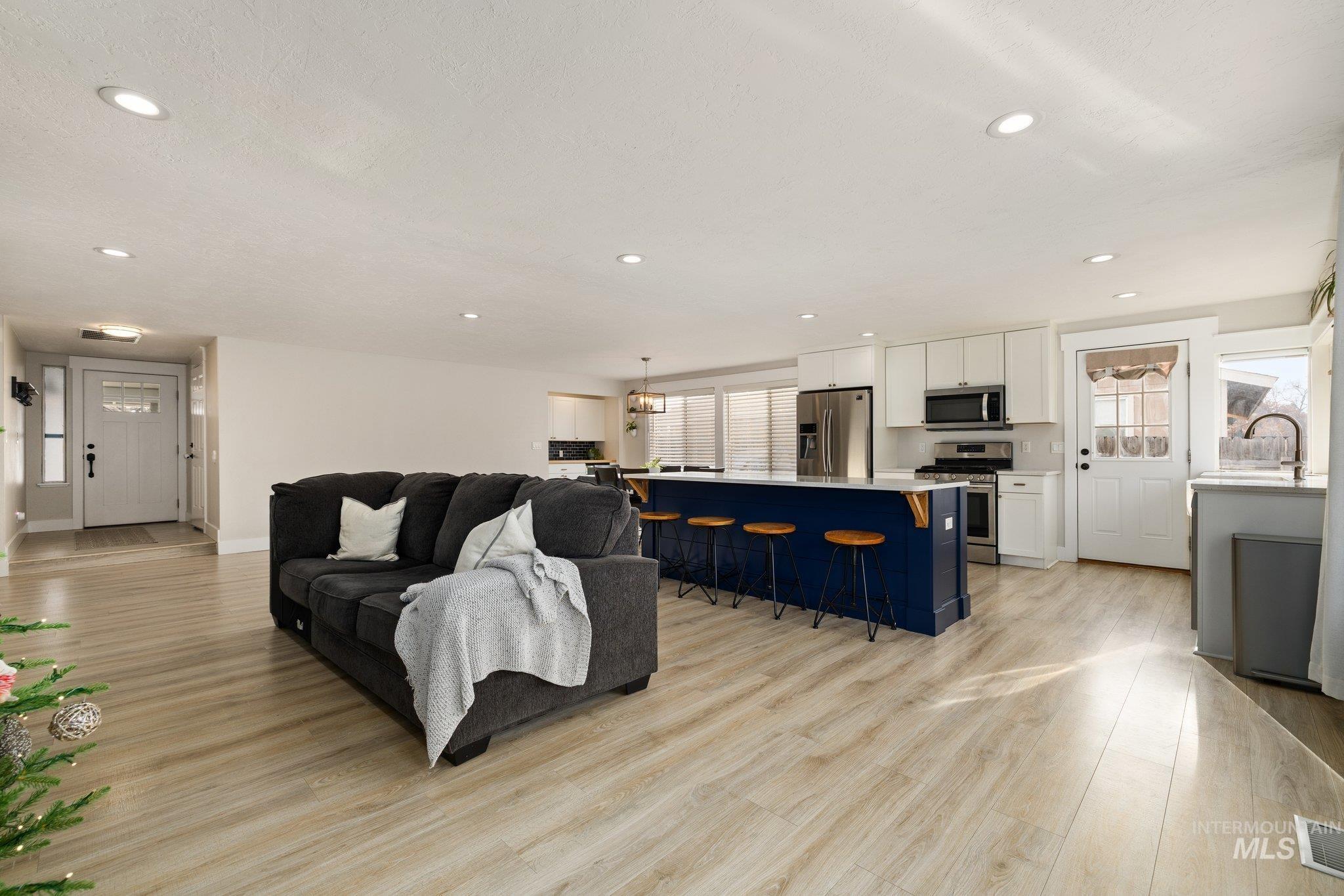 Living area with light wood-type flooring, recessed lighting, and a chandelier
