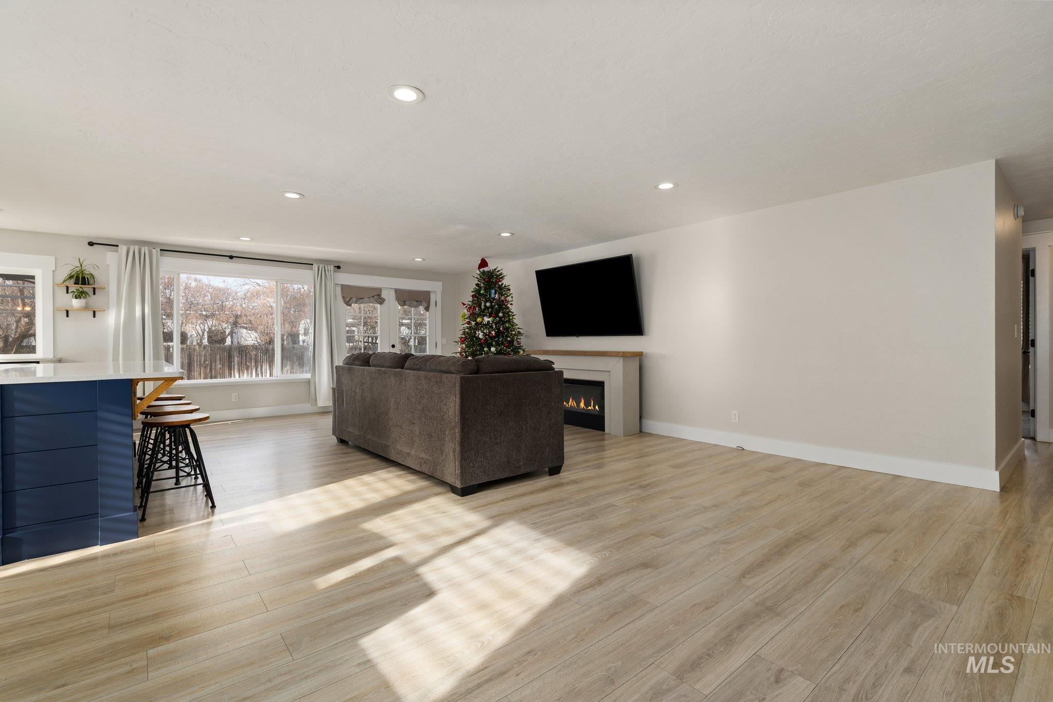 Living room with light wood-type flooring, recessed lighting, and a lit fireplace