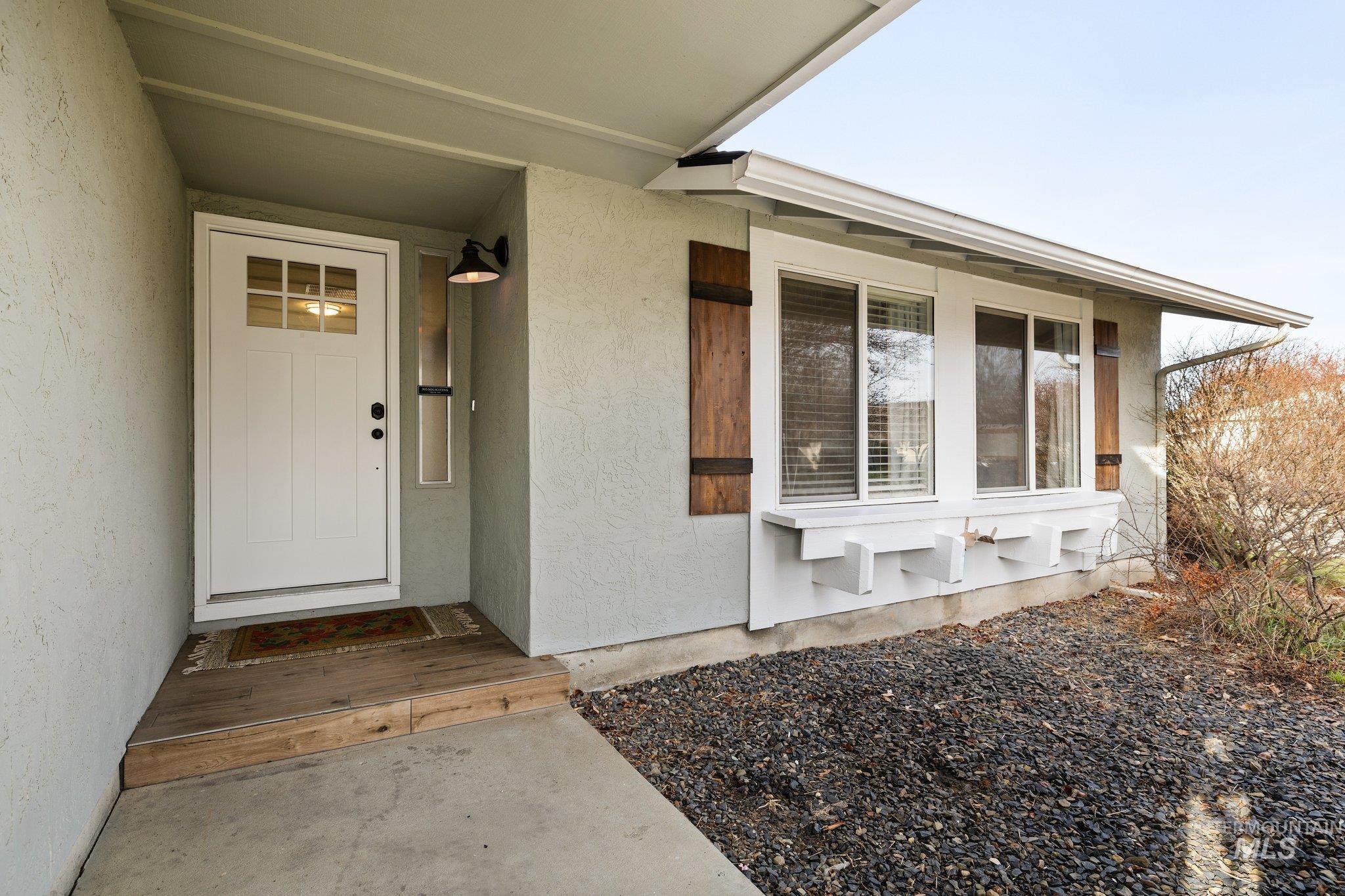 View of exterior entry featuring stucco siding and a porch