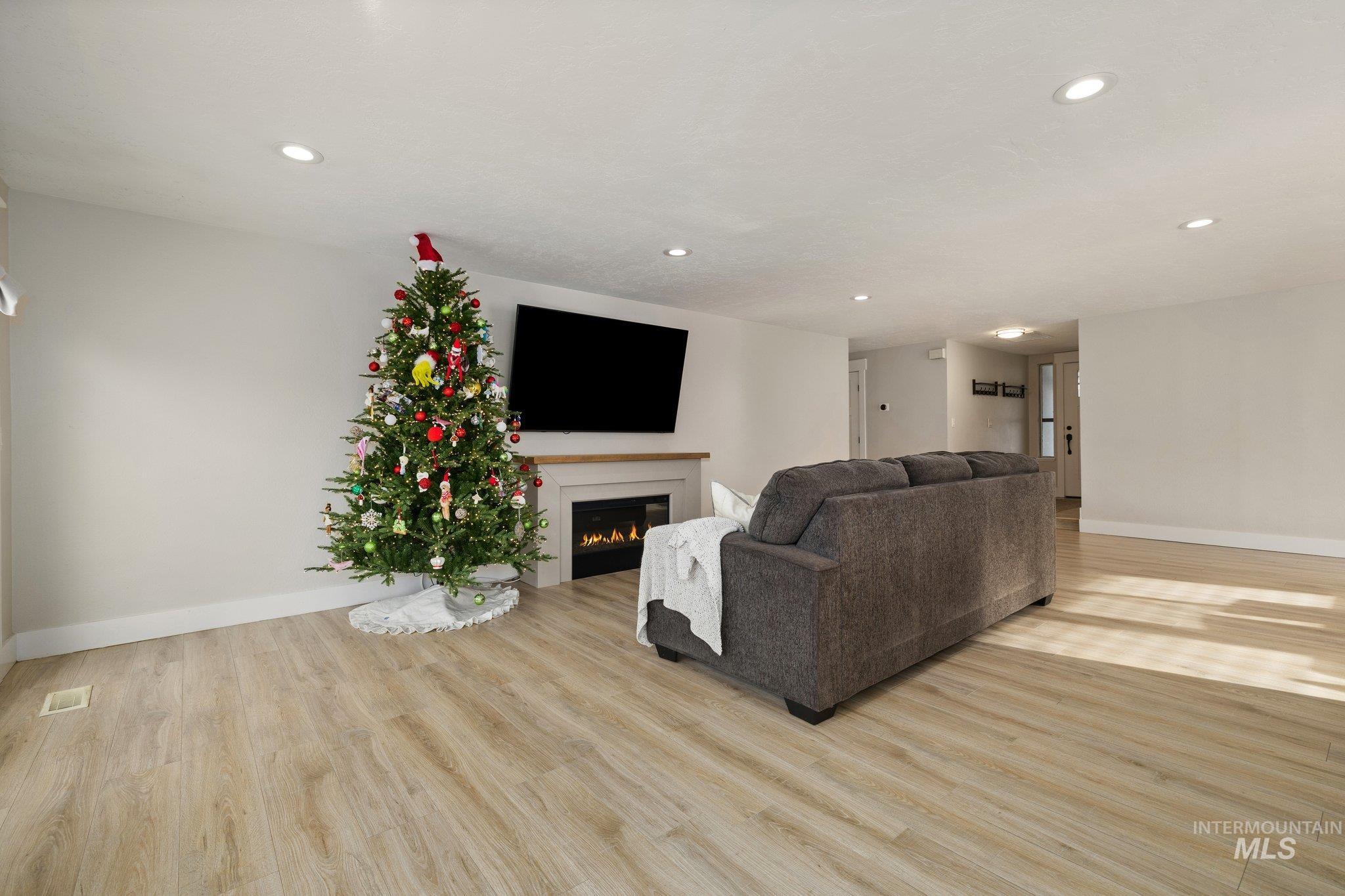 Living area featuring a lit fireplace, light wood-style floors, and recessed lighting