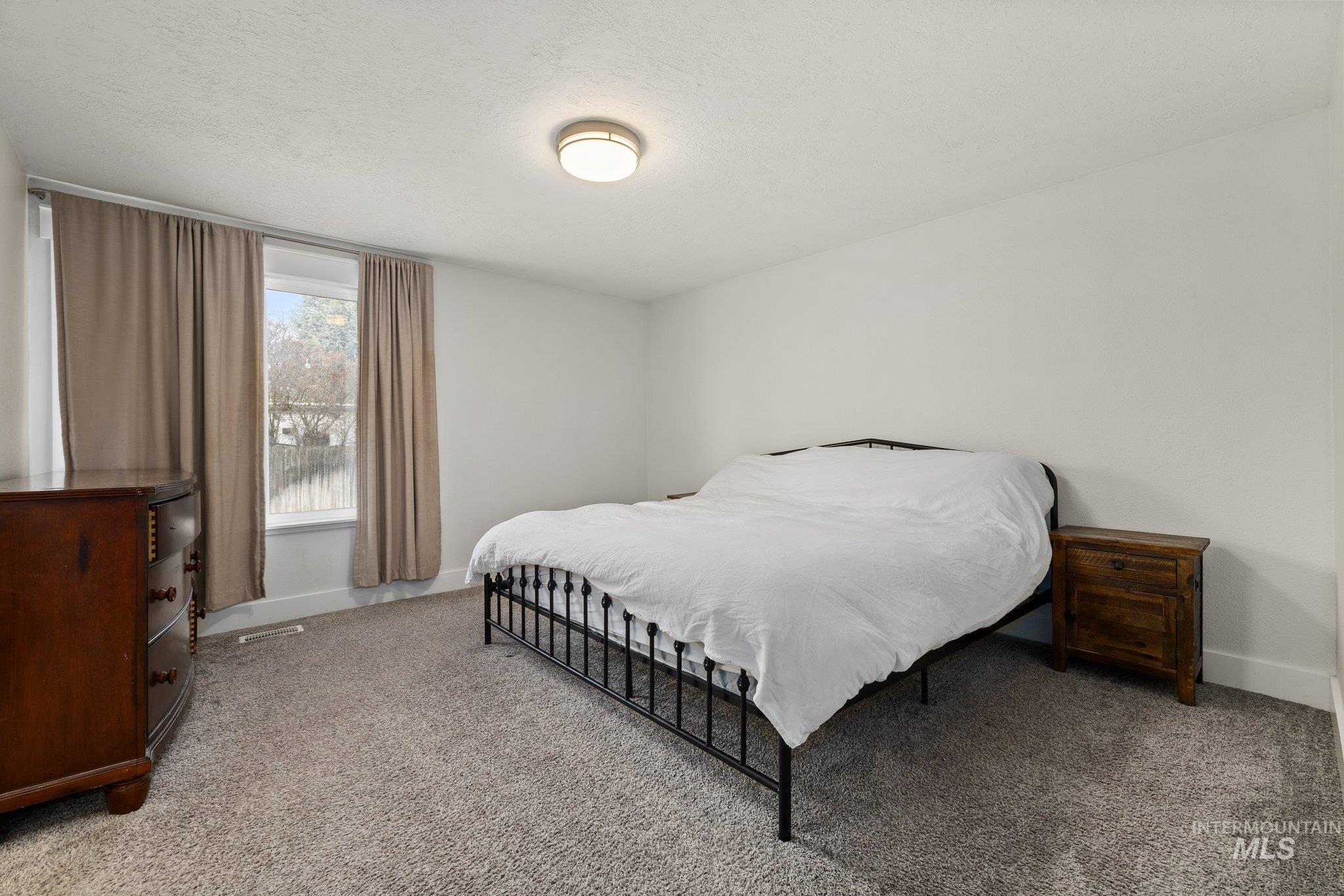 Carpeted bedroom with baseboards and a textured ceiling