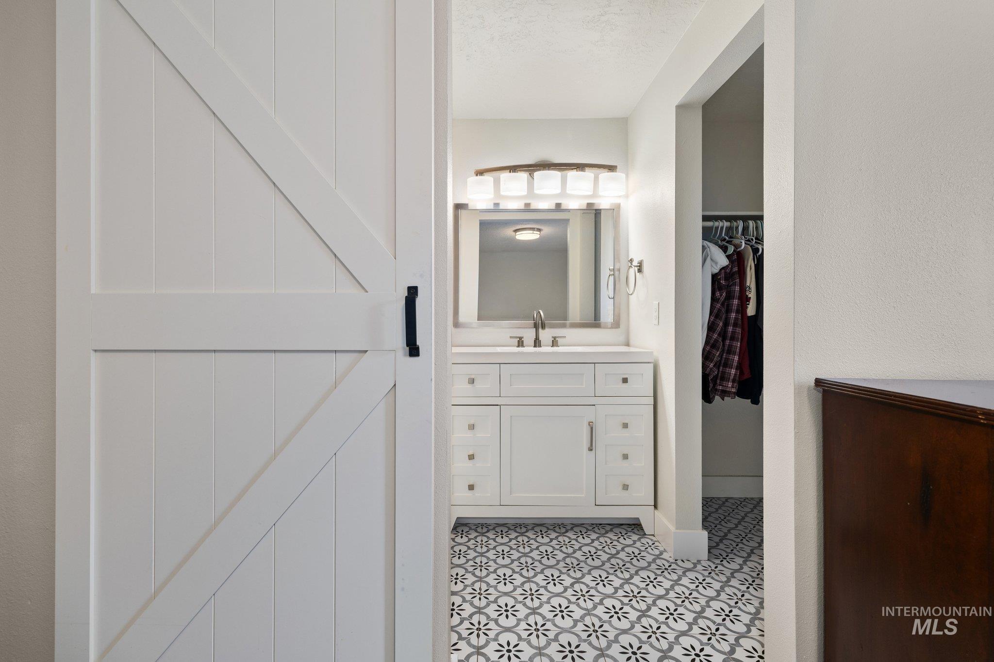 Bathroom featuring vanity, a walk in closet, a textured ceiling, and light tile patterned flooring