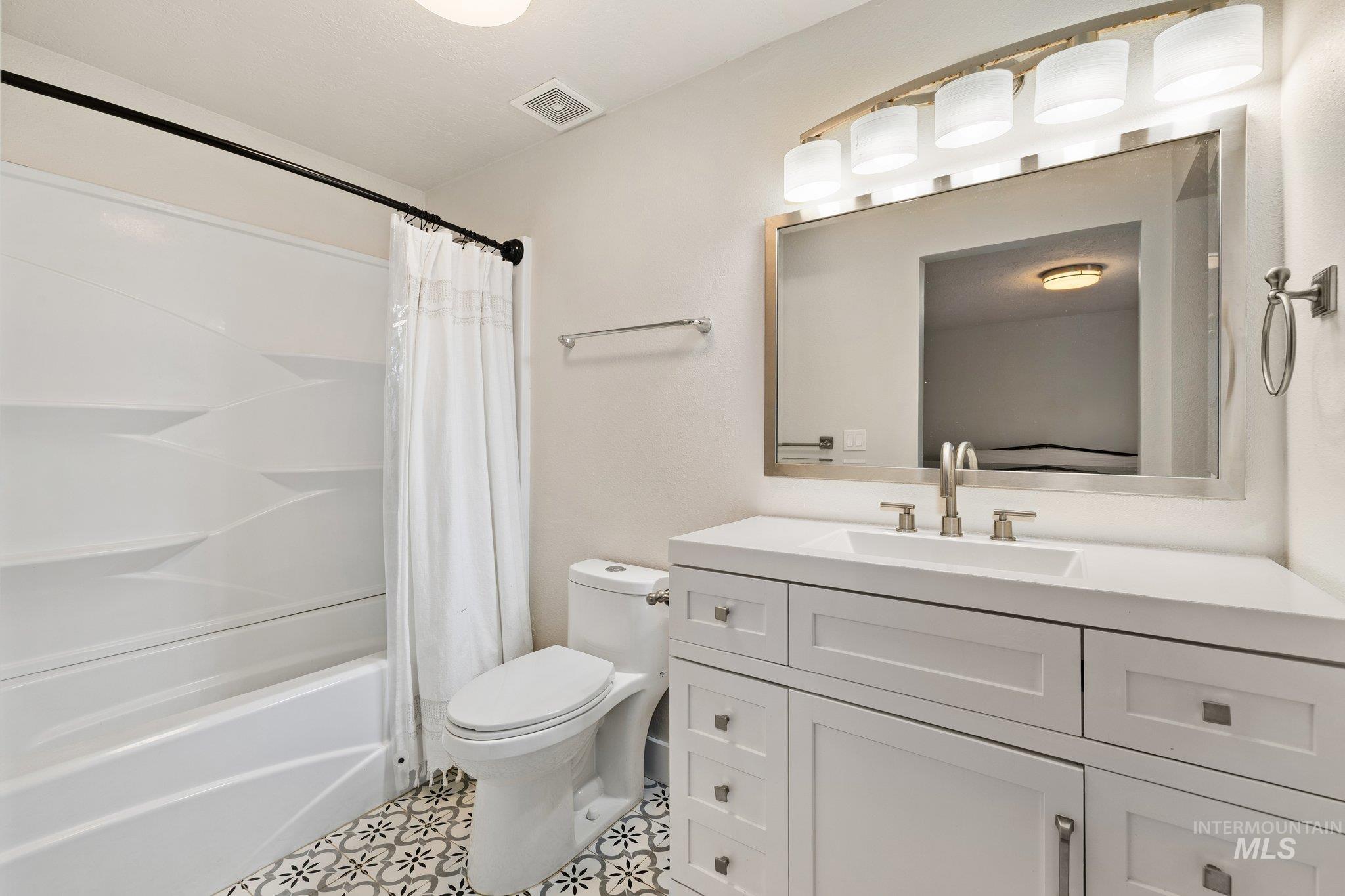 Bathroom with shower / tub combo, vanity, and light tile patterned flooring
