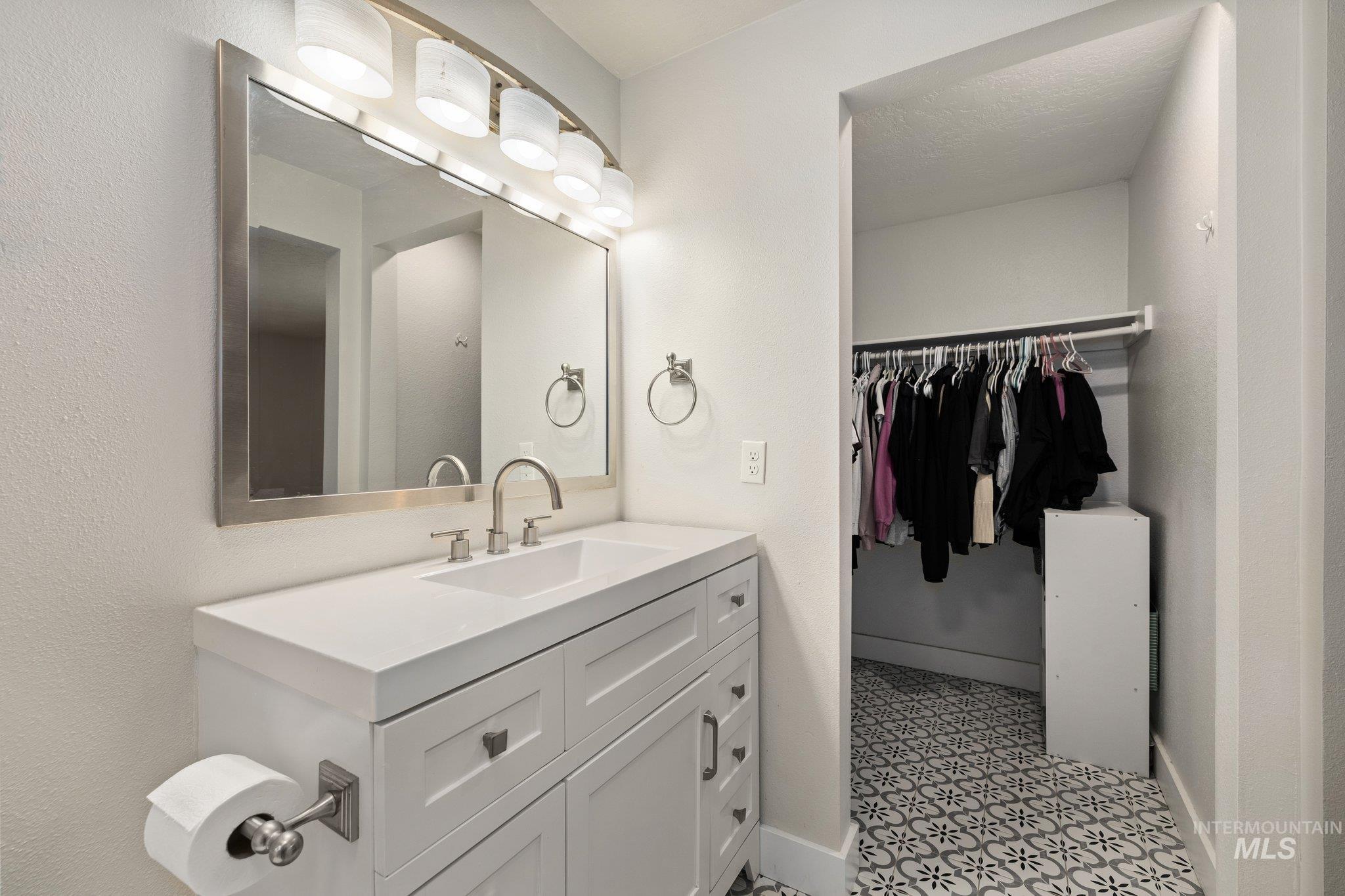 Bathroom featuring vanity, a walk in closet, and a textured wall