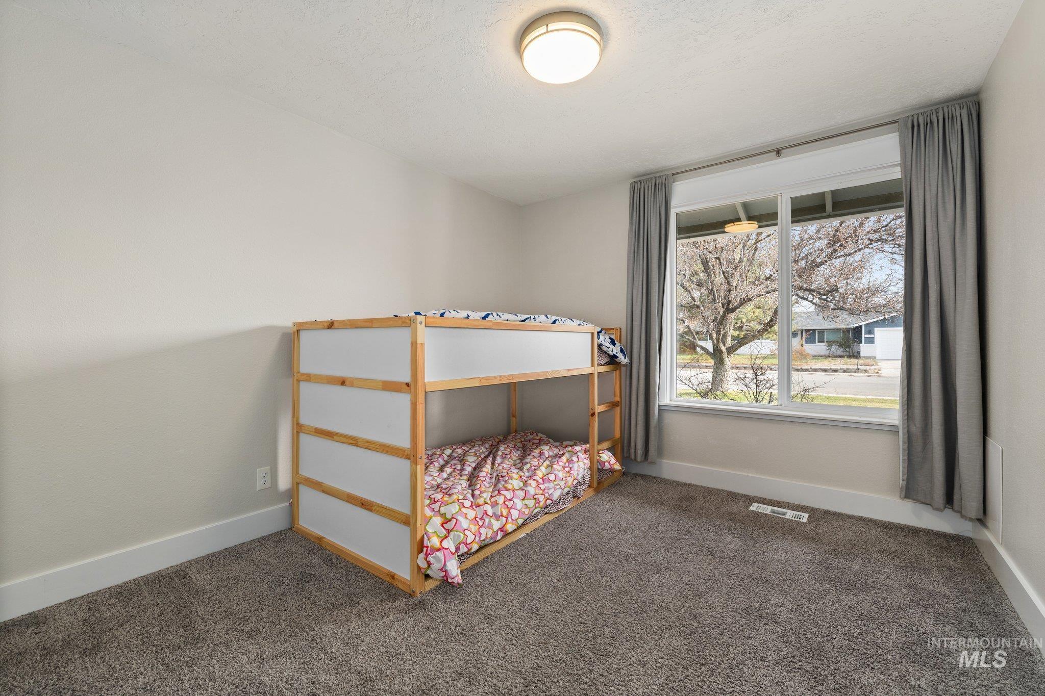 Bedroom with dark colored carpet and a textured ceiling