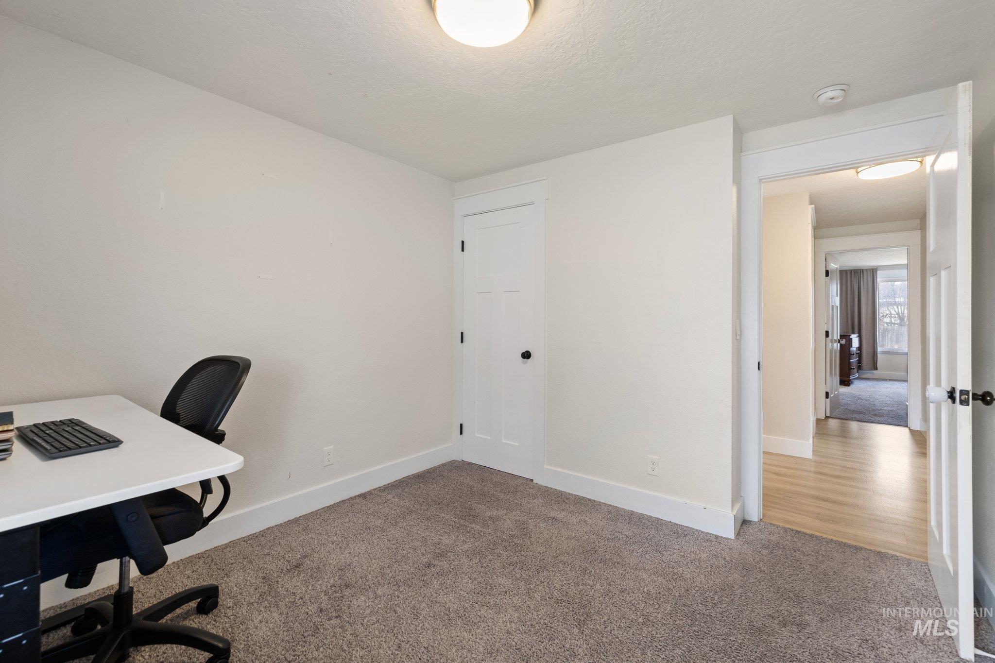 Office with carpet flooring and a textured ceiling