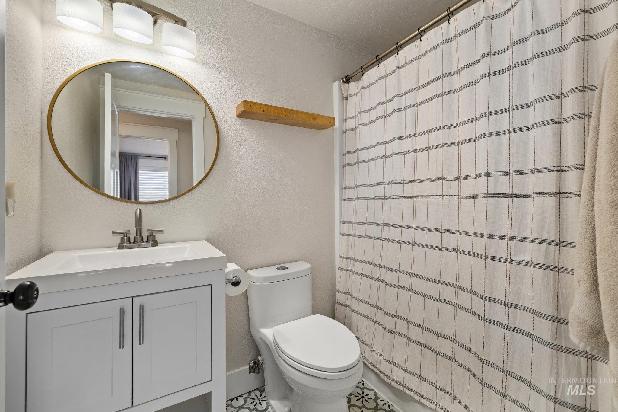 Bathroom with a shower with curtain, vanity, and a textured wall