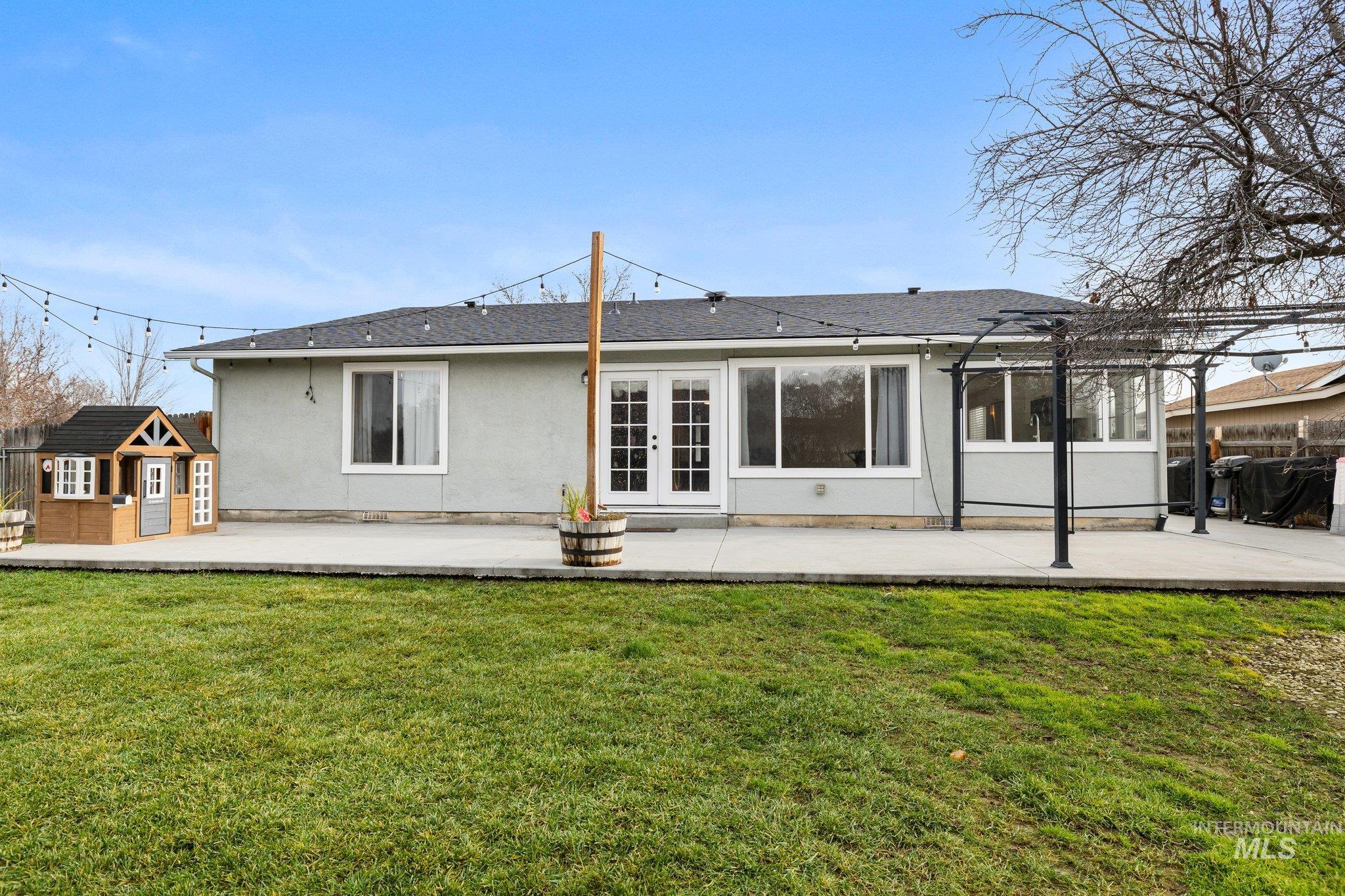 Rear view of property with a patio area, a storage shed, a shingled roof, and stucco siding