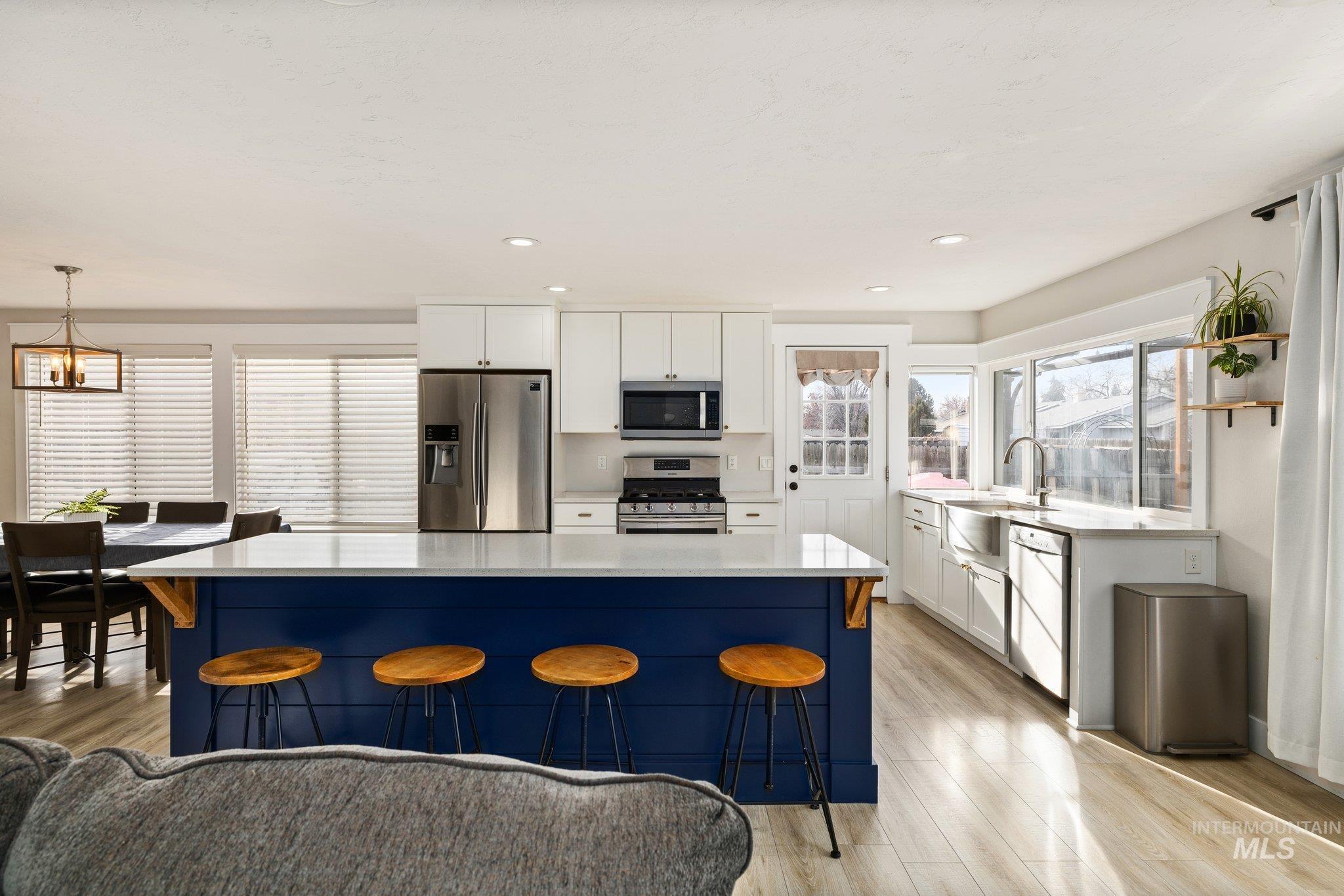 Kitchen with white cabinetry, a kitchen bar, stainless steel appliances, light wood finished floors, and a kitchen island