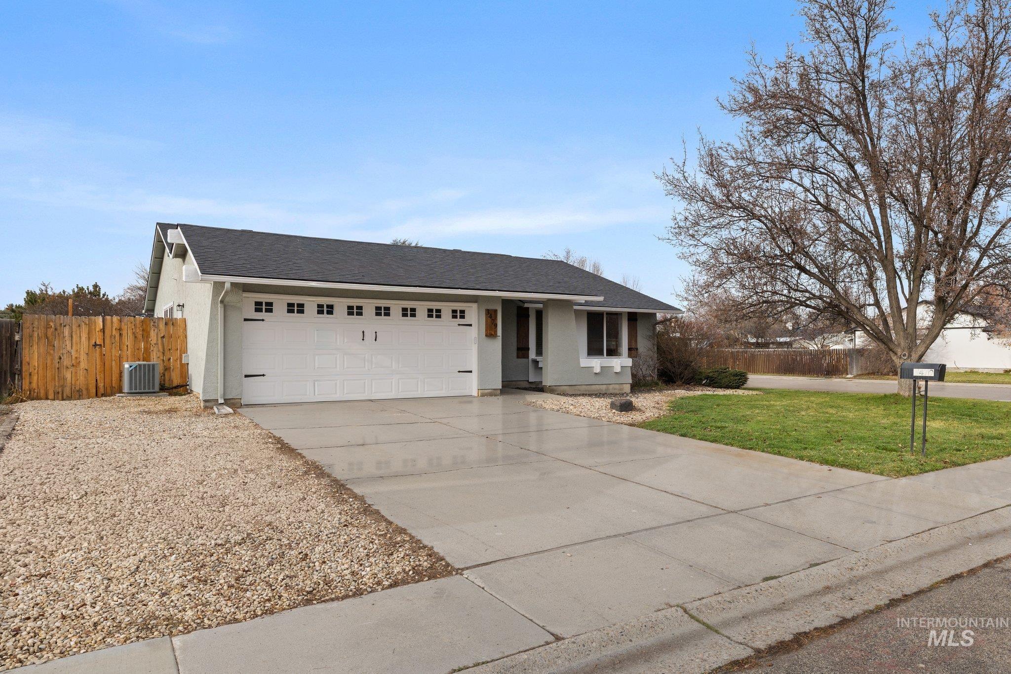 Ranch-style house with a shingled roof, concrete driveway, an attached garage, and stucco siding