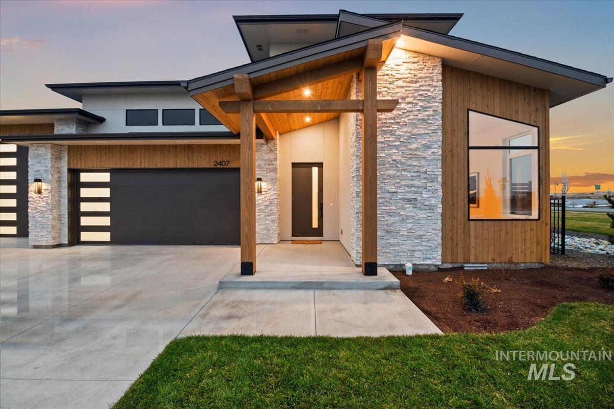 Contemporary house with stone siding, a garage, and driveway