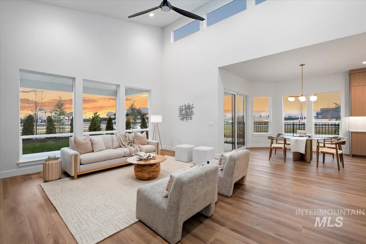 Living room with light wood-style flooring, recessed lighting, a towering ceiling, and ceiling fan