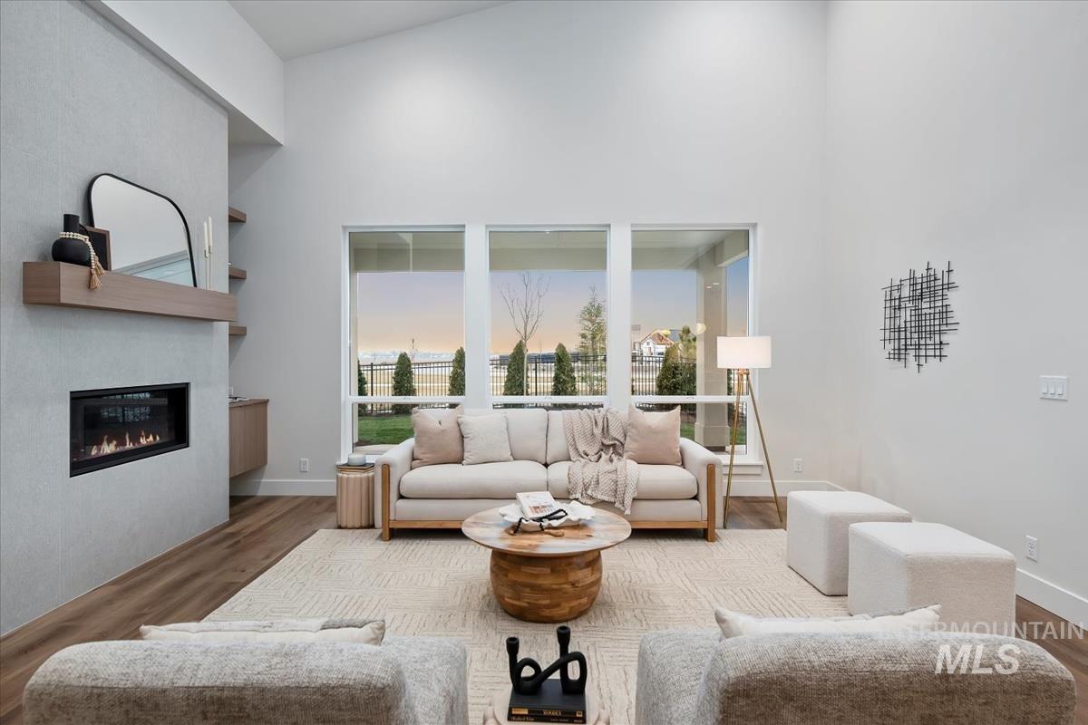 Living area featuring wood finished floors, a glass covered fireplace, and a high ceiling