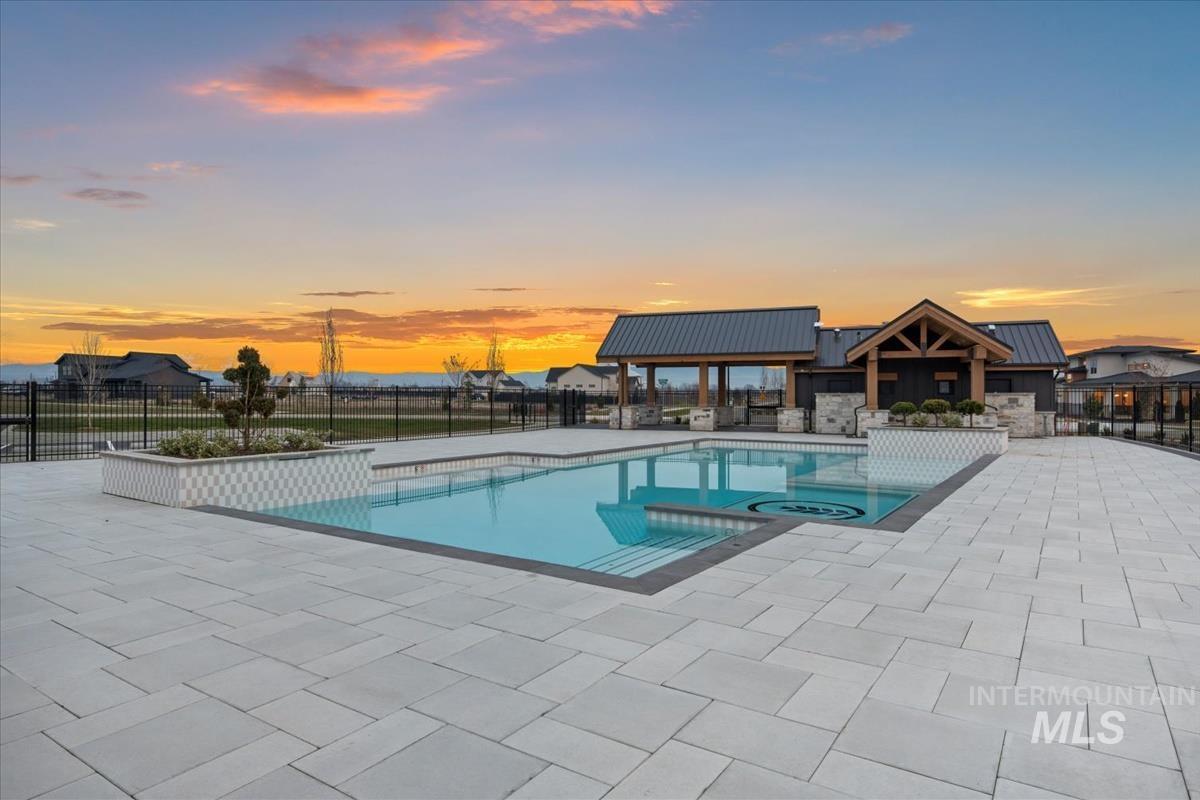 Pool at dusk with a patio and a pool with connected hot tub