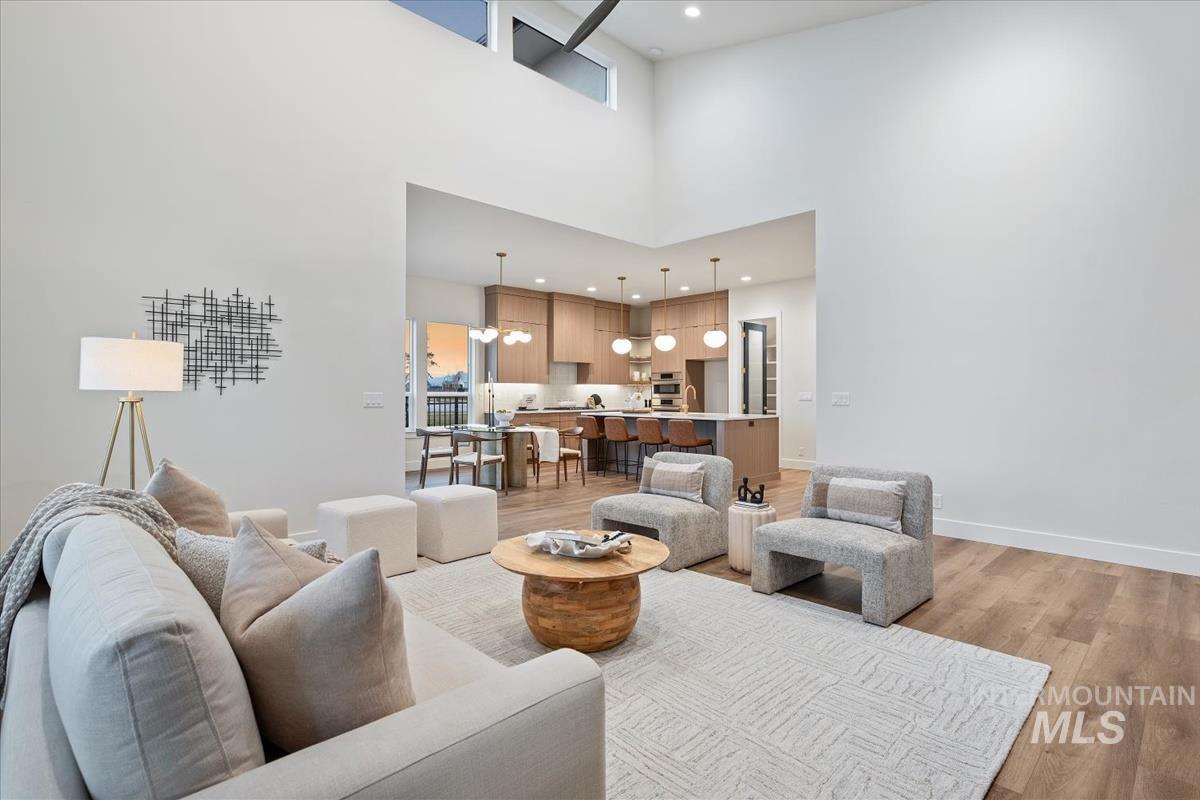Living area featuring recessed lighting, light wood-style flooring, a chandelier, and a towering ceiling