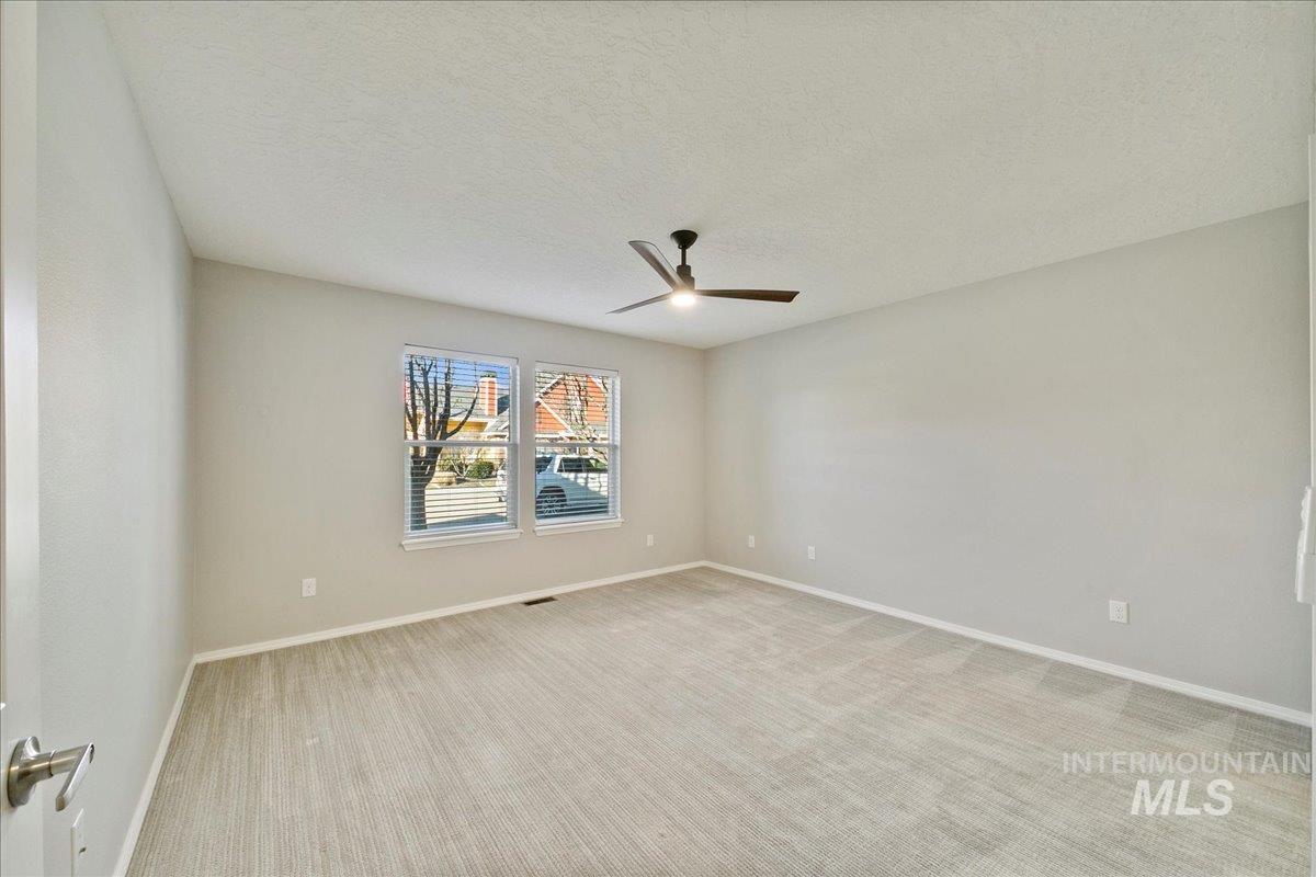 Unfurnished room with a textured ceiling, light colored carpet, and ceiling fan