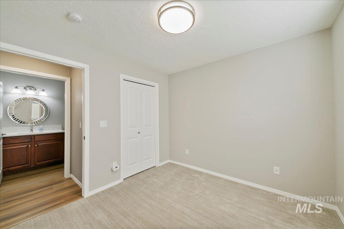 Unfurnished bedroom featuring a textured ceiling, light carpet, and a closet