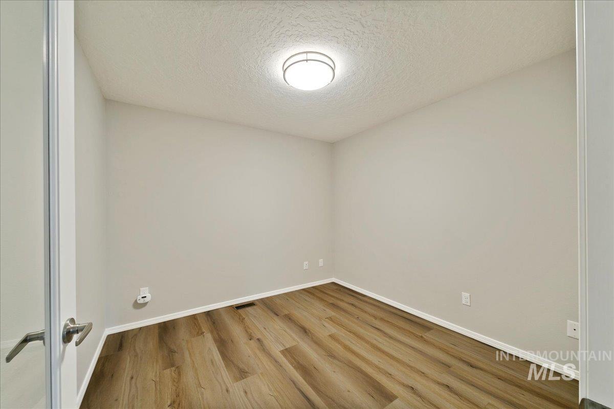 Empty room with a textured ceiling and wood finished floors