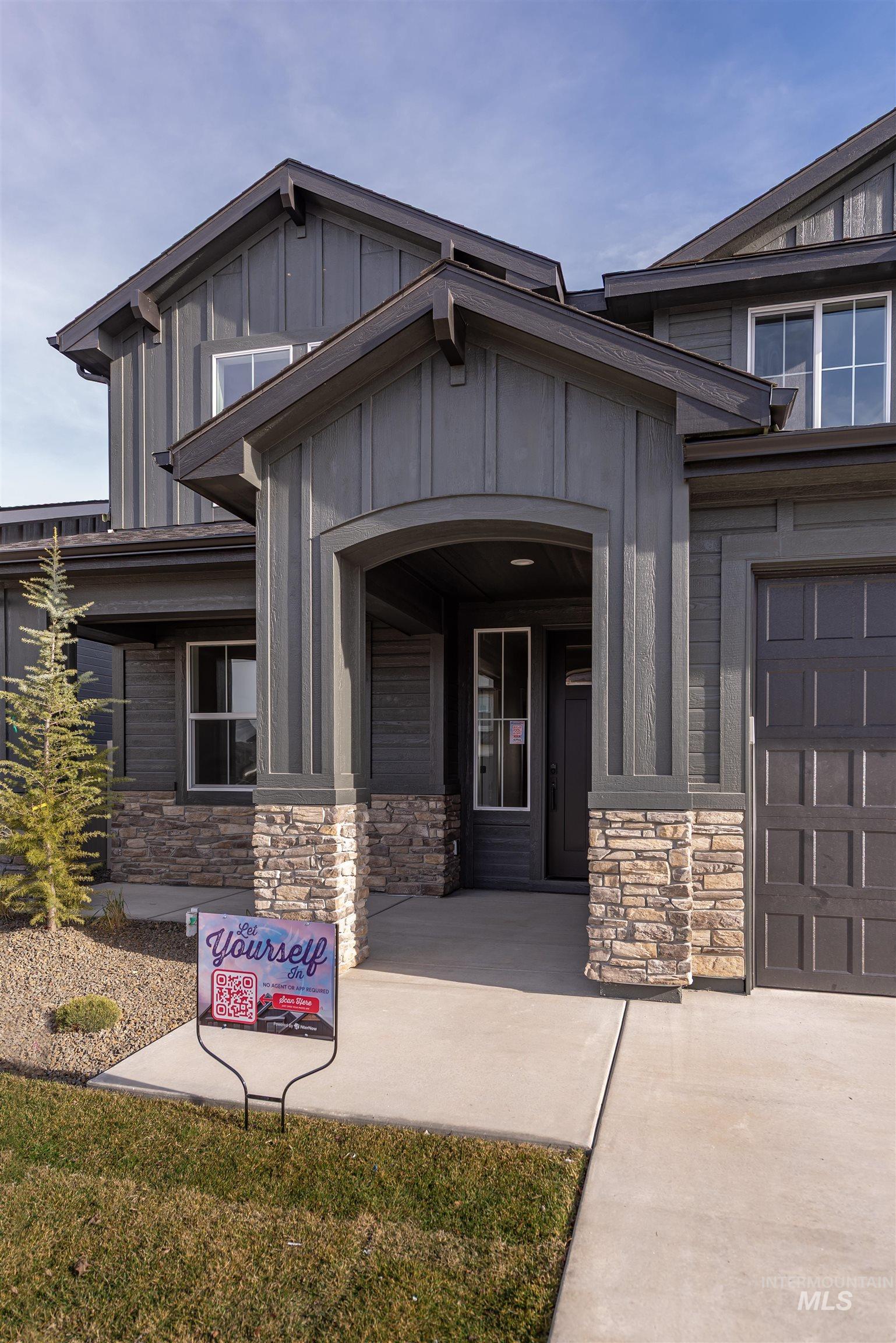 View of exterior entry with stone siding, board and batten siding, a garage, and covered porch