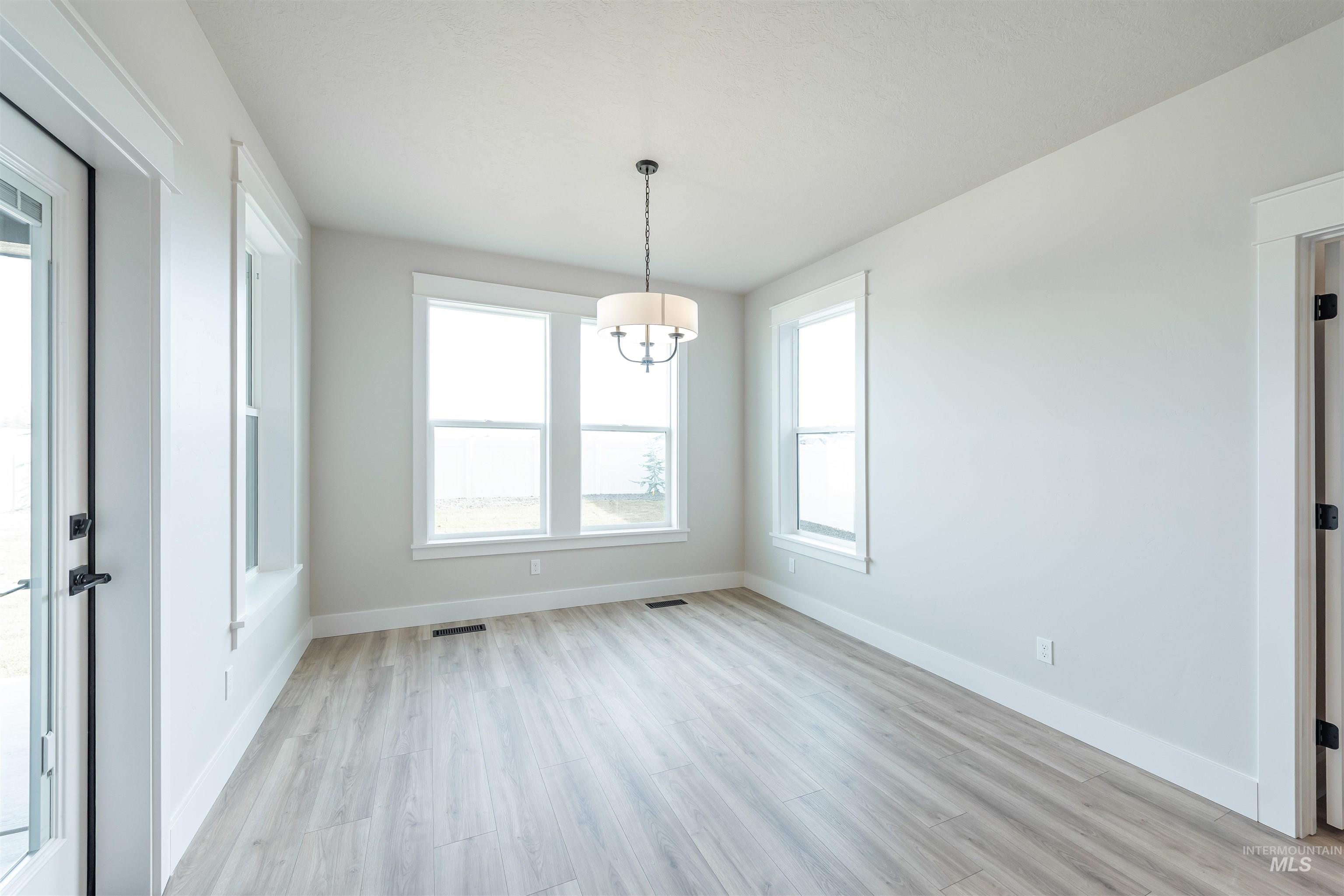 Unfurnished dining area featuring light wood finished floors and a chandelier