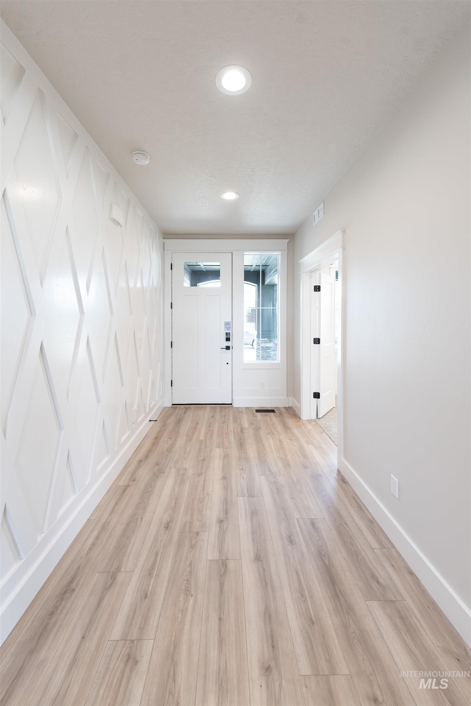 Foyer entrance with light wood-style floors and recessed lighting