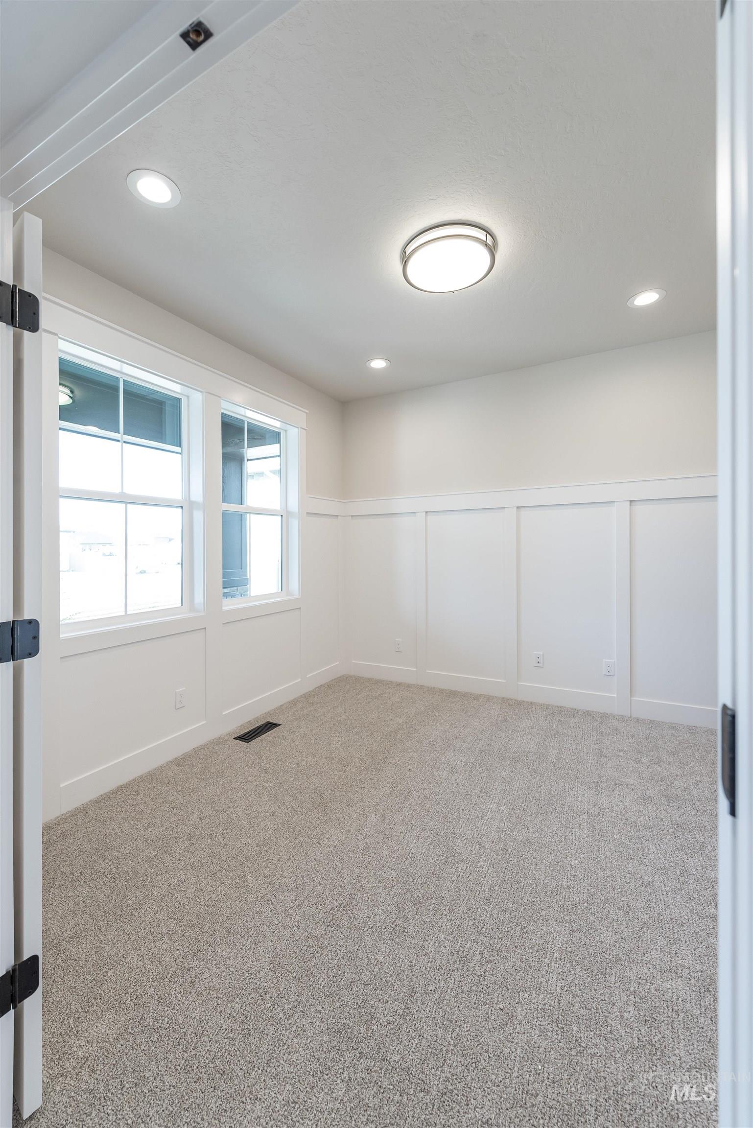 Unfurnished room with a decorative wall, light carpet, a wainscoted wall, and recessed lighting