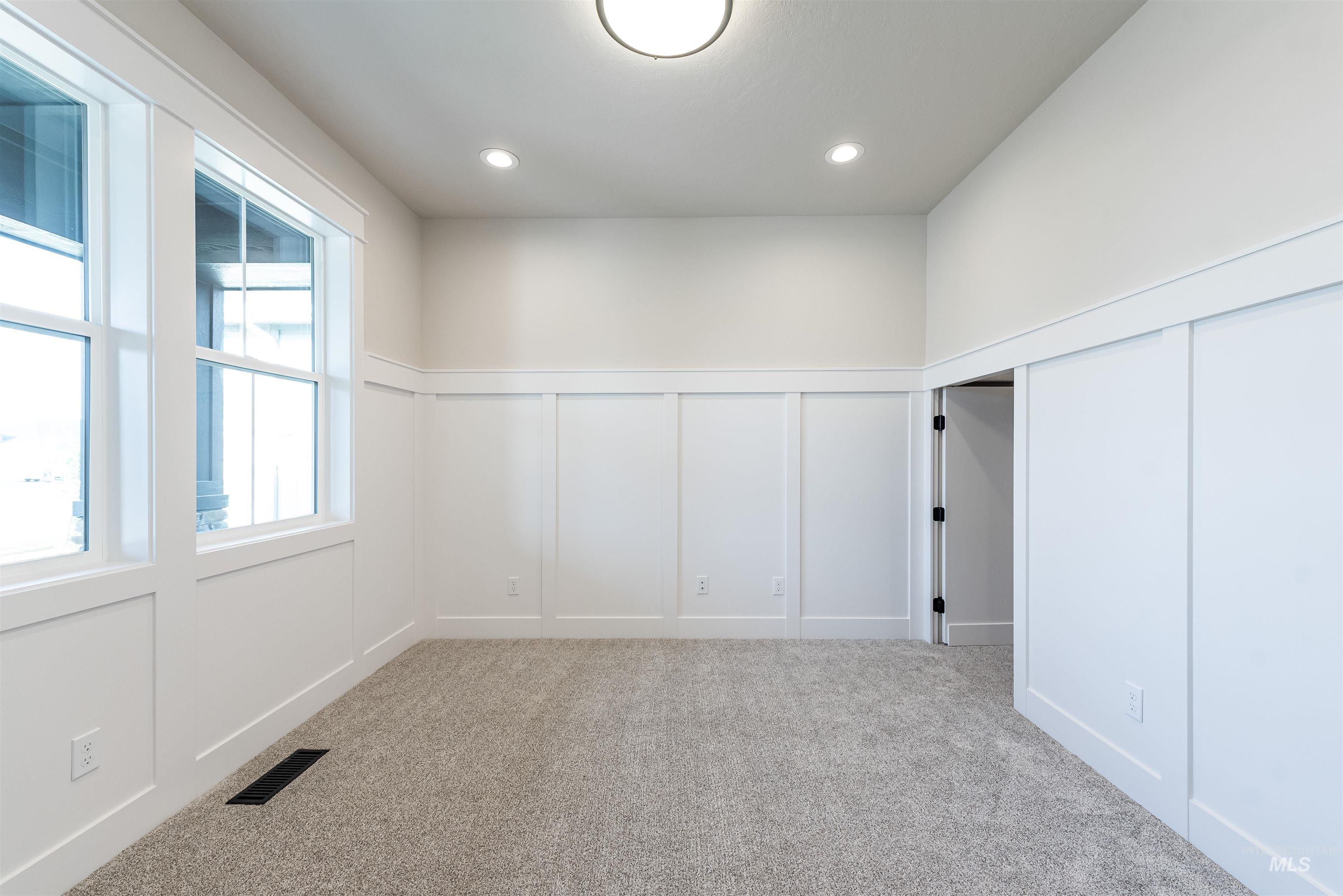 Spare room with a decorative wall, a wainscoted wall, light colored carpet, and recessed lighting